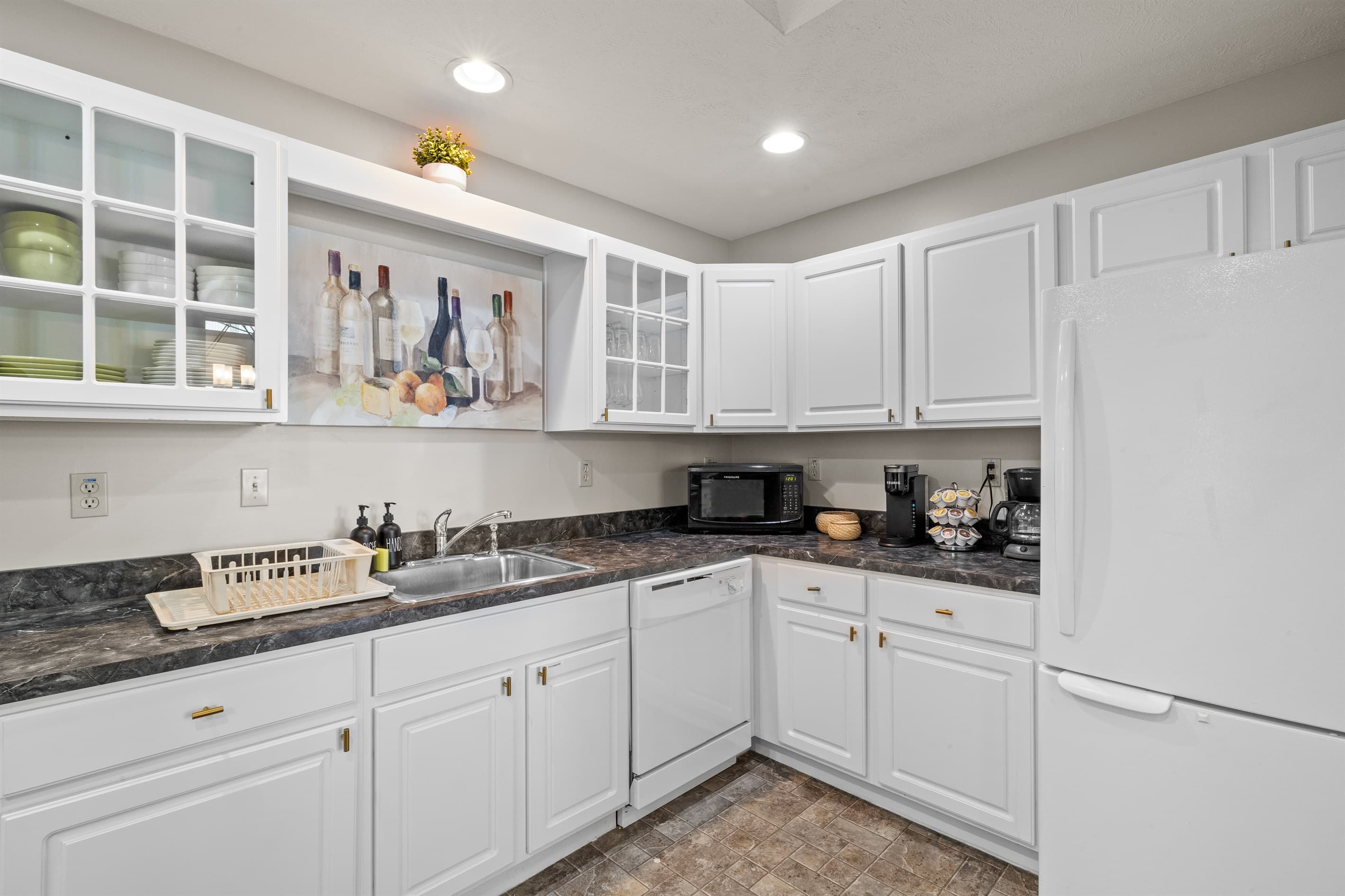 Fully stocked kitchen with white appliances, stainless sink, dishwasher, microwave, toaster, and coffee maker.