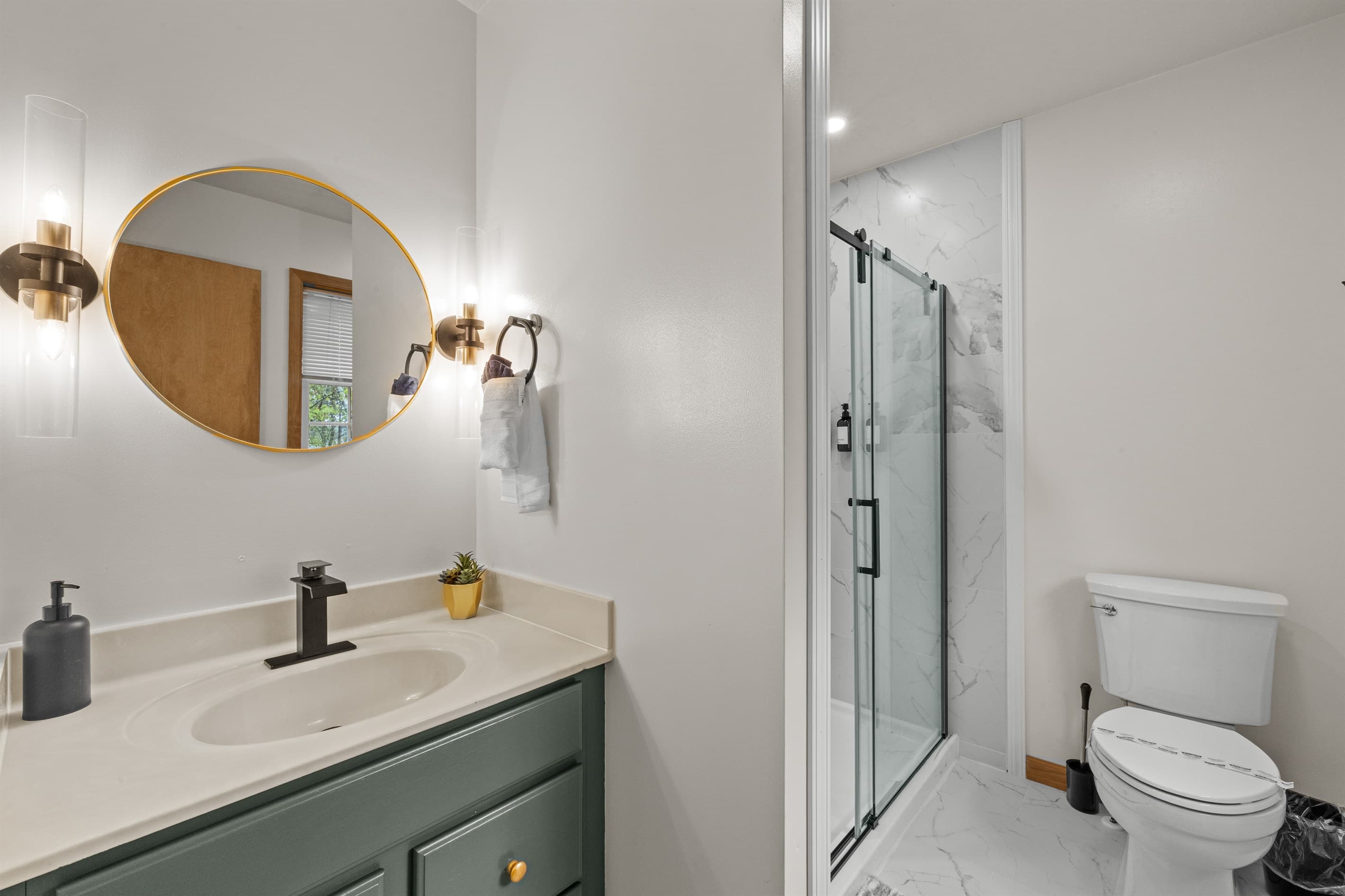 Ensuite bathroom featuring a sink, mirror, toilet, and walk-in shower for convenience and comfort.