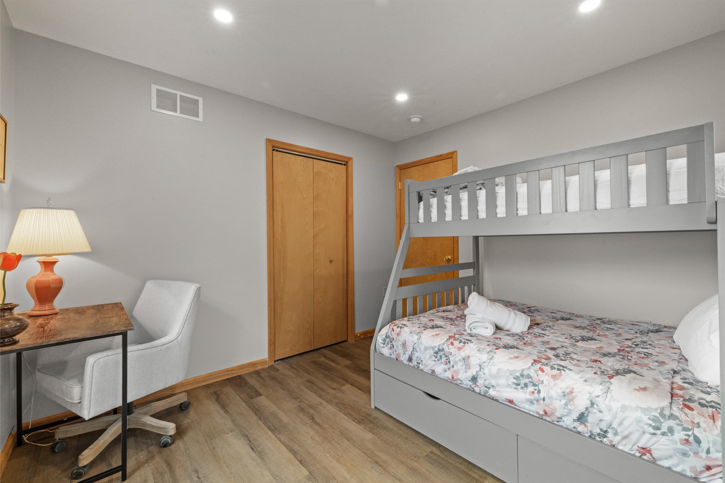 Cozy bedroom with a twin-over-full bunk bed and a small workspace, perfect for kids or remote work.