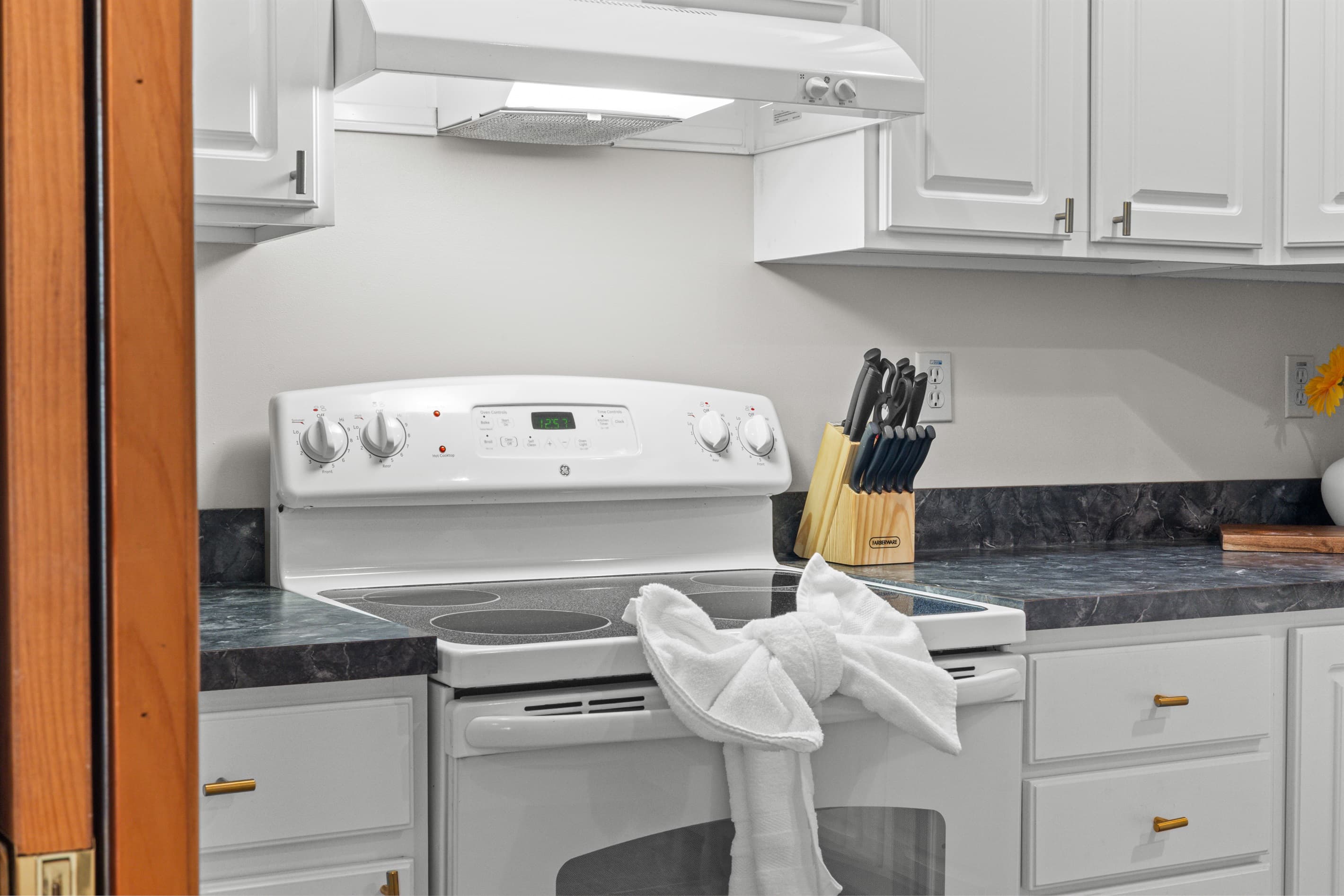 Fully stocked kitchen with white appliances, stainless sink, dishwasher, microwave, toaster, and coffee maker.