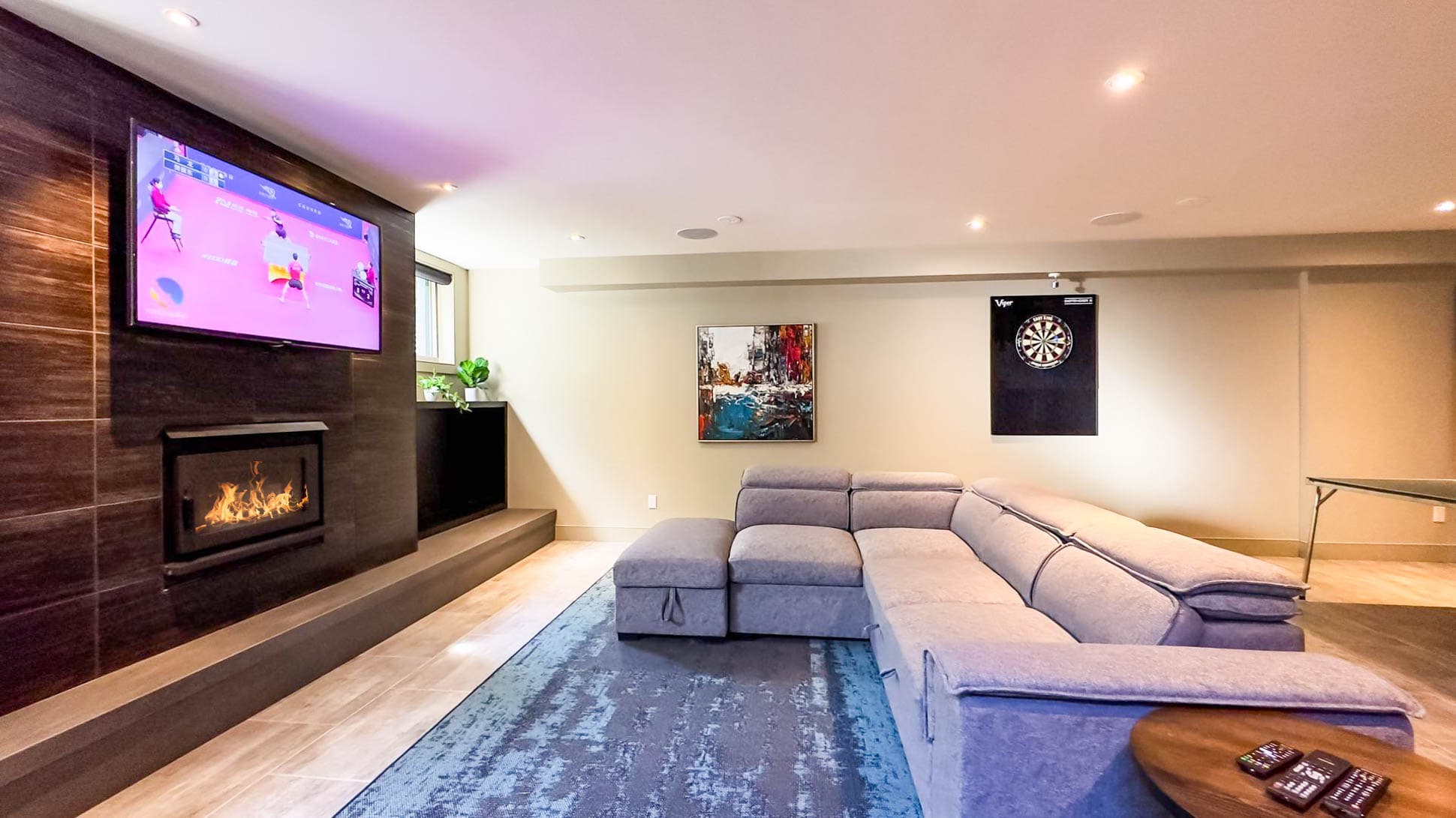 The trifecta of coziness: a large couch, TV, and a crackling fireplace