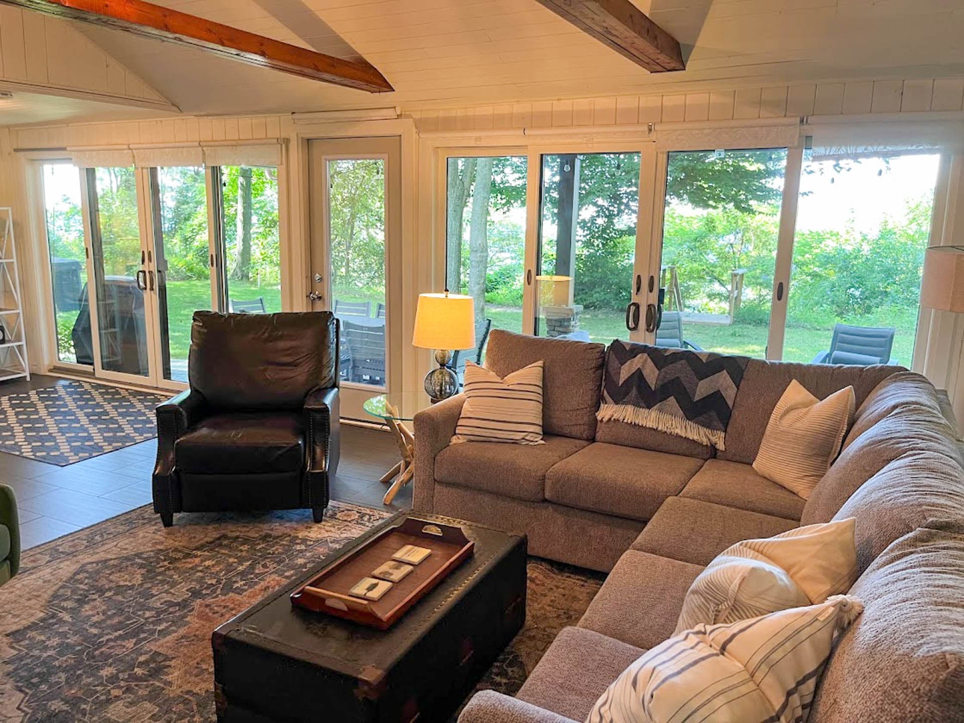 Exposed beams, white paneled walls and ceilings and tons of light give the living room a beach chic feel.