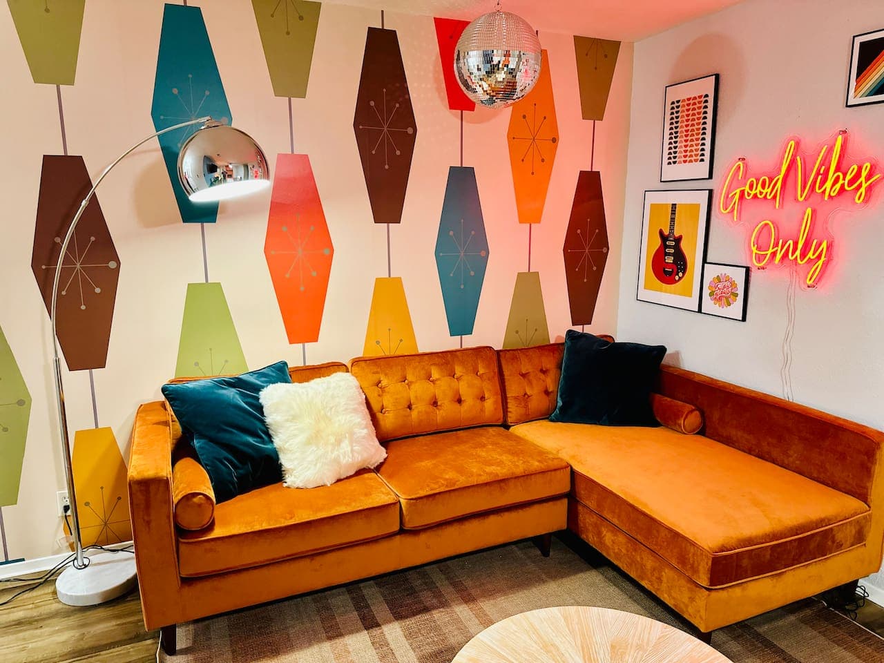 Step back in time with our retro living room featuring a vibrant orange sofa and a glowing neon sign.