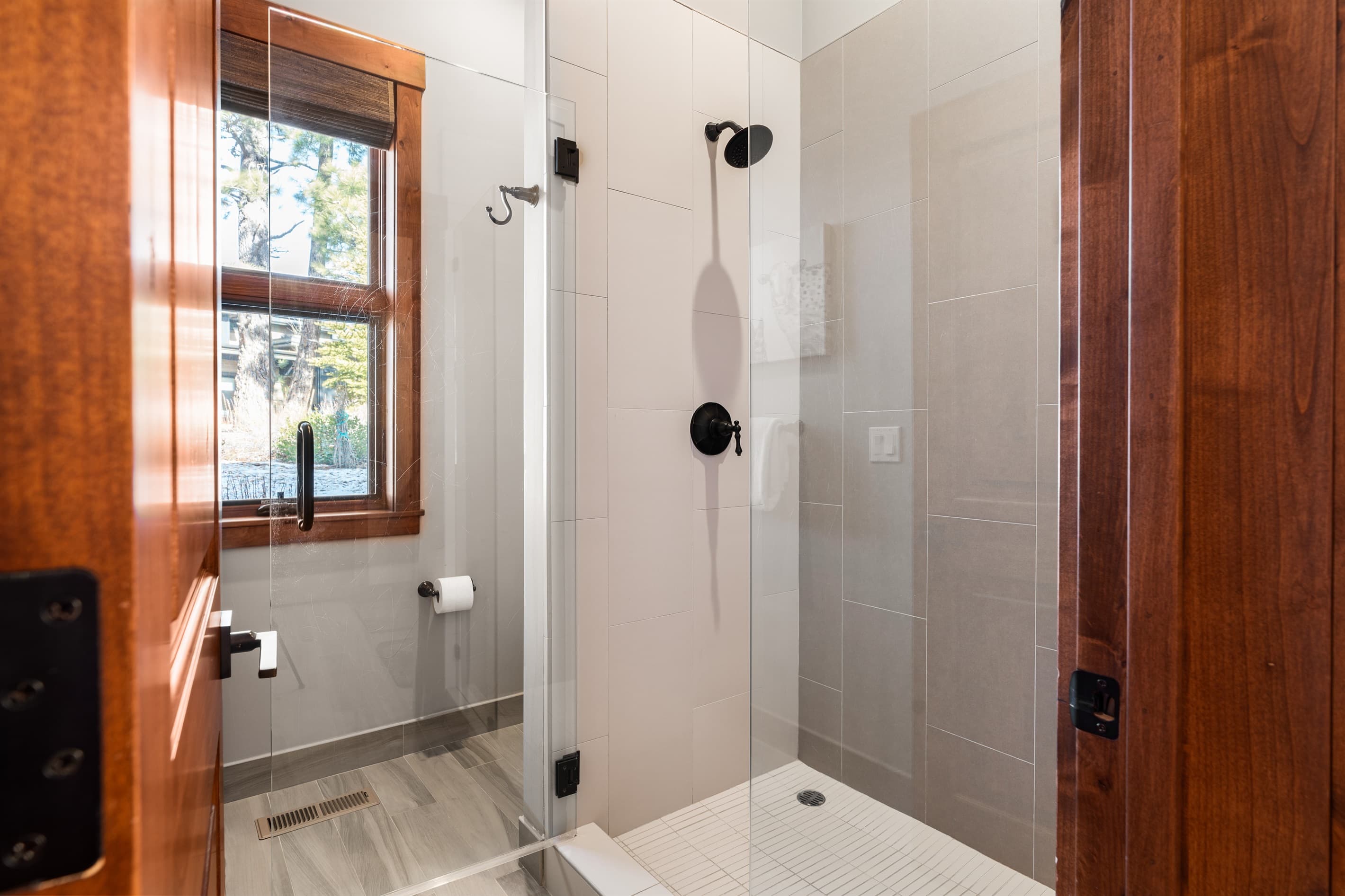 The spa-like primary bathroom features dual vanities and a walk-in shower, creating a serene space for relaxation. Essentials such as toilet paper, hand soap, shampoo, conditioner, and body wash are provided for your convenience.