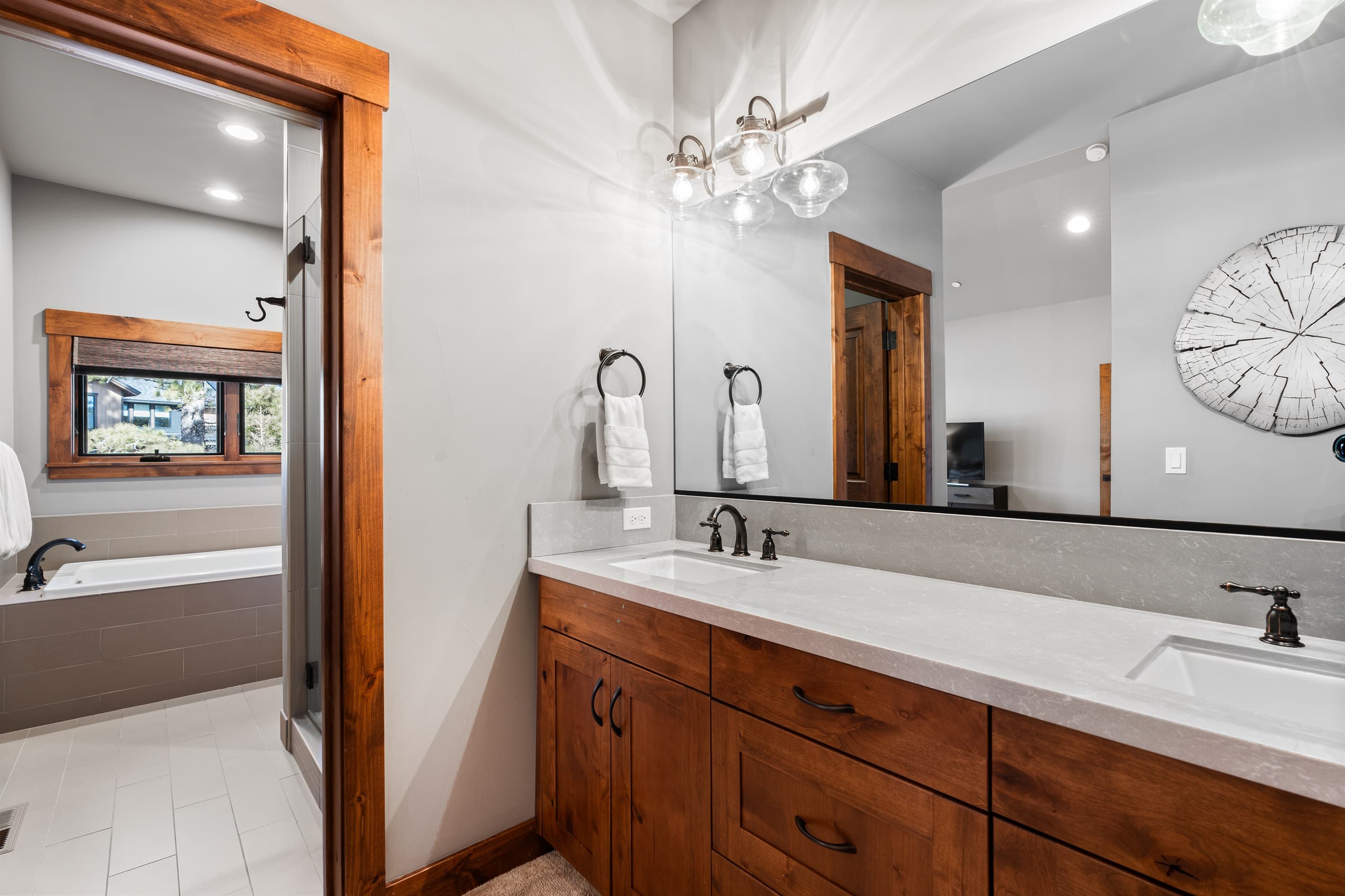 This bathroom features dual vanities, a soaking tub, and a spacious walk-in shower, offering both style and functionality. Thoughtfully stocked with shampoo, conditioner, and body wash for a comfortable and convenient stay.