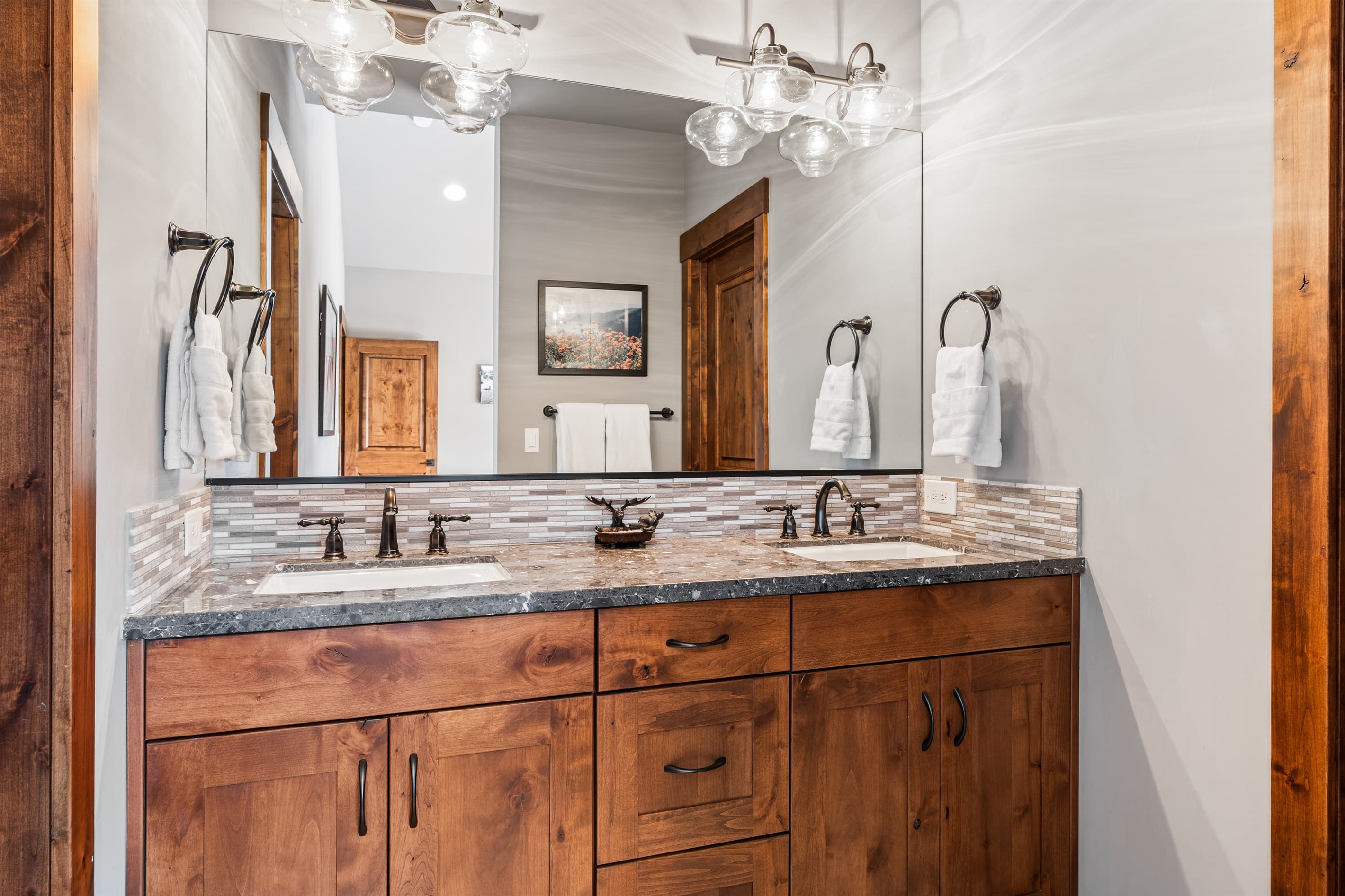 This bathroom features dual vanities and a spacious walk-in shower, providing both style and functionality. Thoughtfully stocked with shampoo, conditioner, and body wash for a comfortable stay.