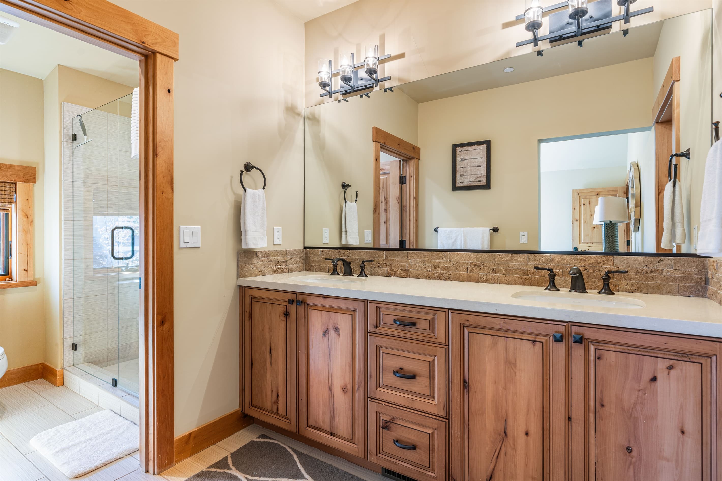 The bunk room bathroom offers a walk-in closet, dual vanities, and a spacious walk-in shower, creating a serene space designed for relaxation. Stocked with towels, hand soap, shampoo, conditioner, body wash and toilet paper.