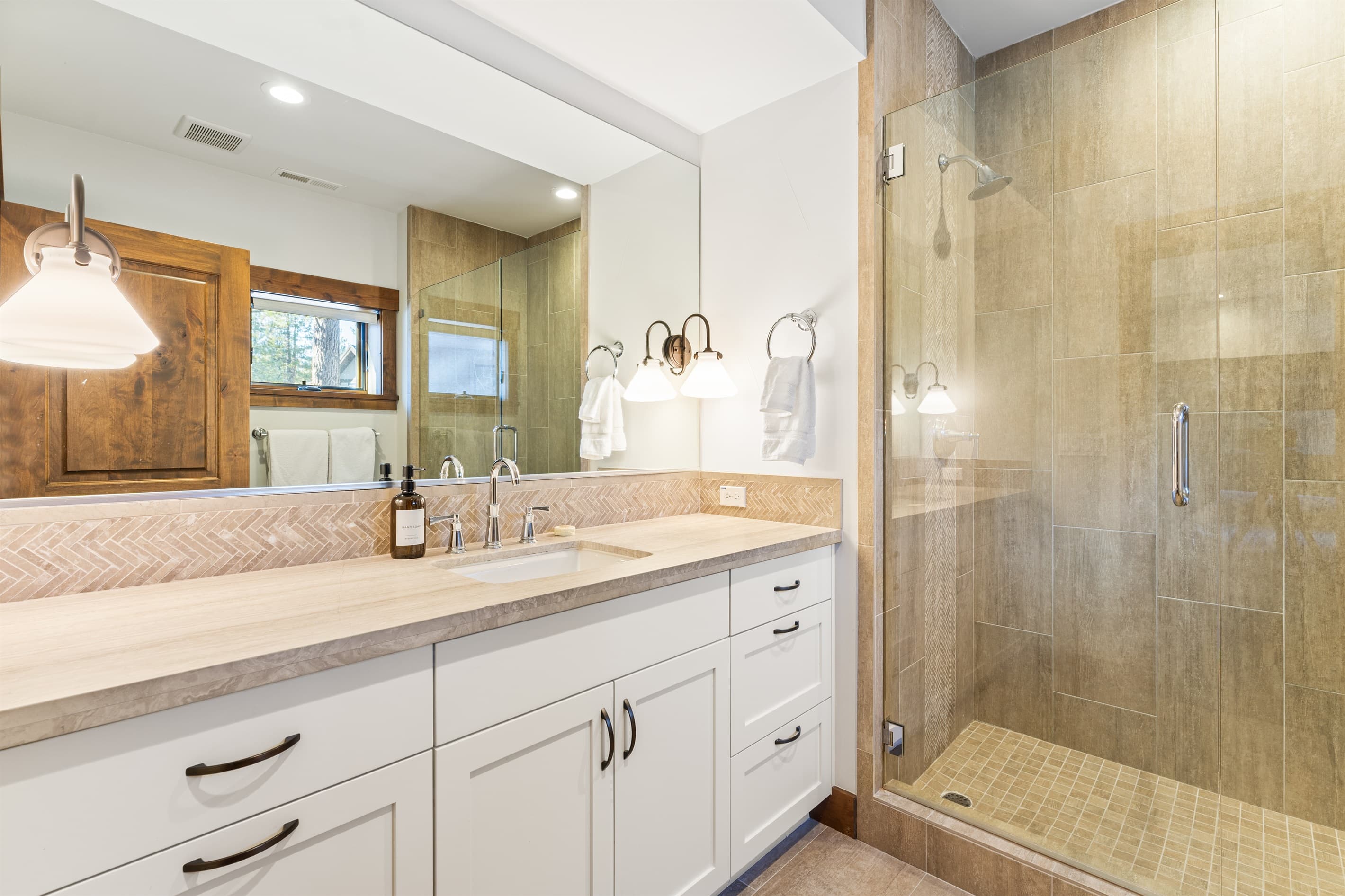 This bathroom features a single vanity and a spacious walk-in shower, providing both style and functionality. Thoughtfully stocked with shampoo, conditioner, and body wash for a comfortable stay.