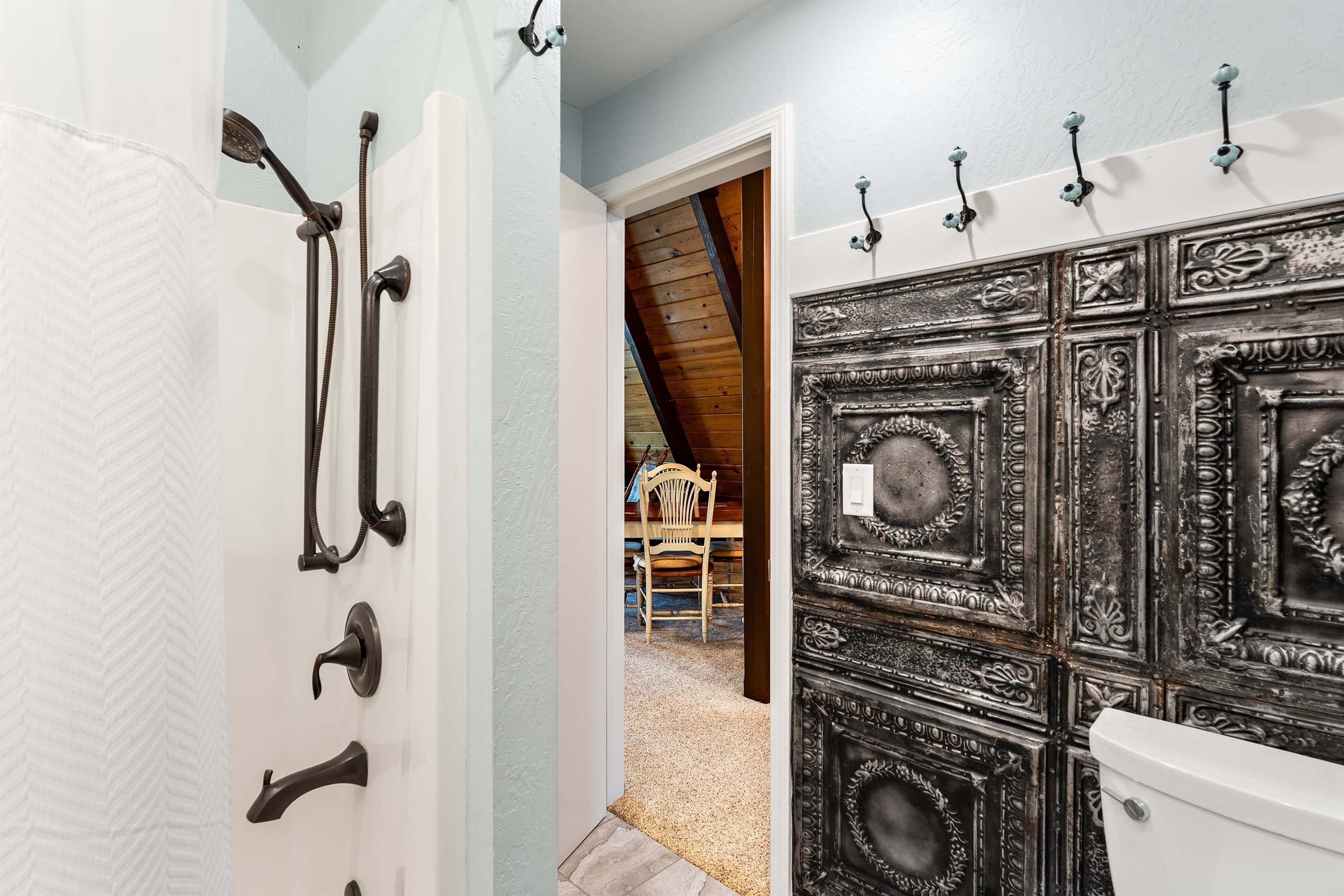 The upstairs bedroom features a queen bed, a ceiling fan, and access to the upper deck with fresh mountain views. It also connects to the Jack and Jill bathroom for added convenience.