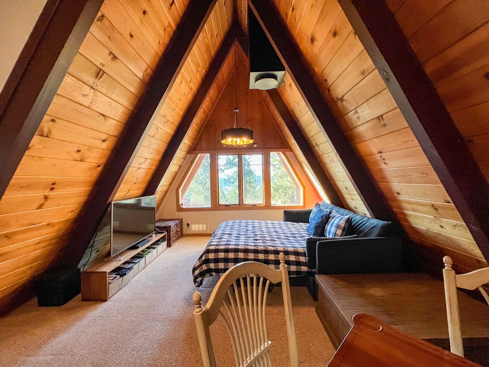 Relax and recharge in the upstairs living room featuring a 55" Smart TV, a cozy card table for game night, direct access to the upper patio, and a sofa bed for additional sleeping space.
