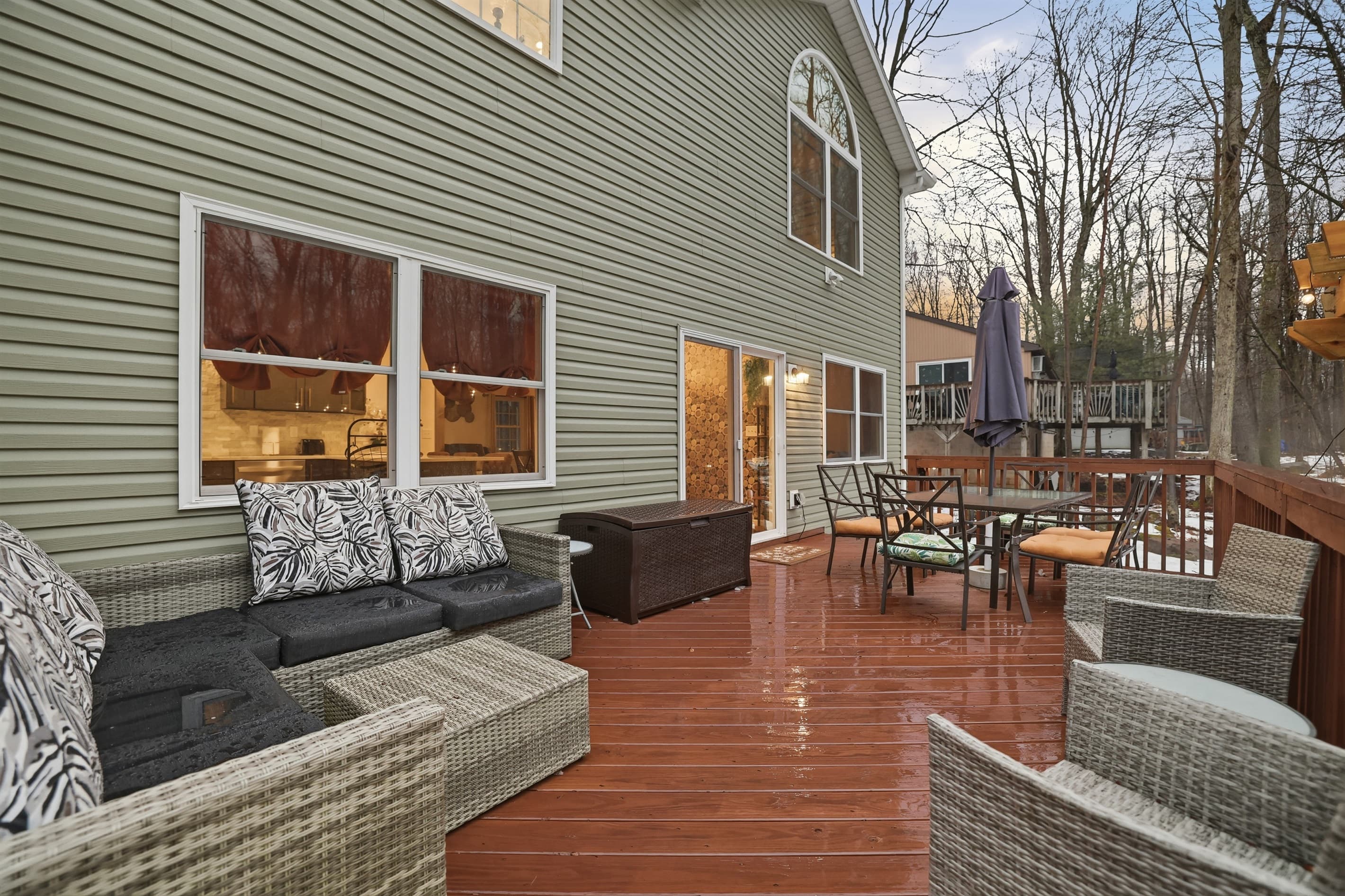 Deck in the back of the house with seating, table with umbrella