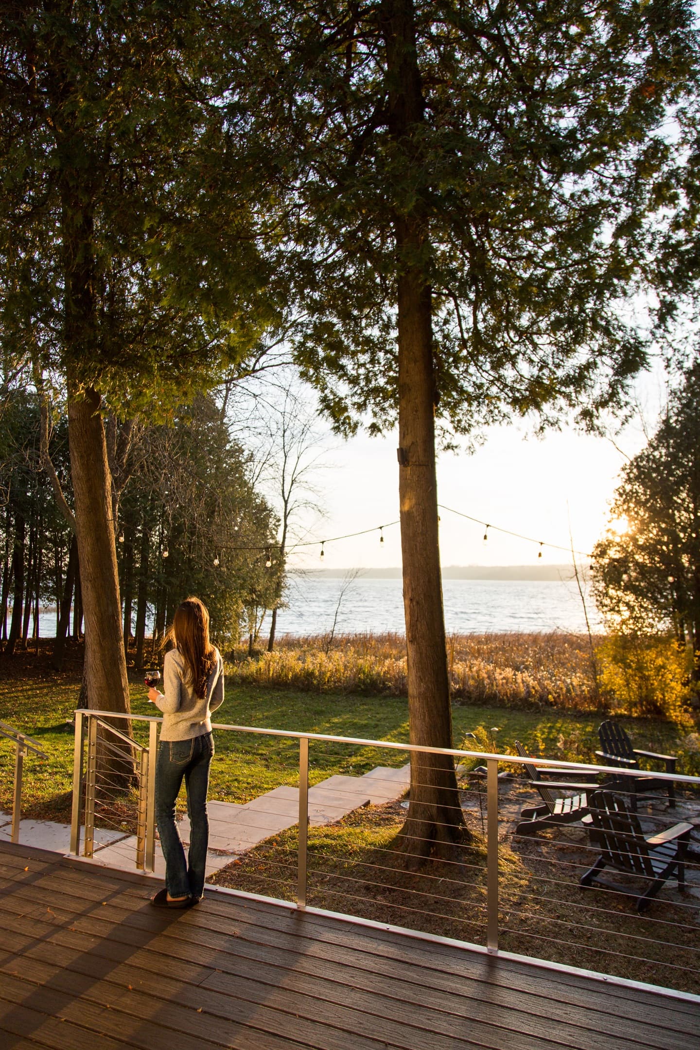 A lake, glass of wine and twinkly lights at the cabin.