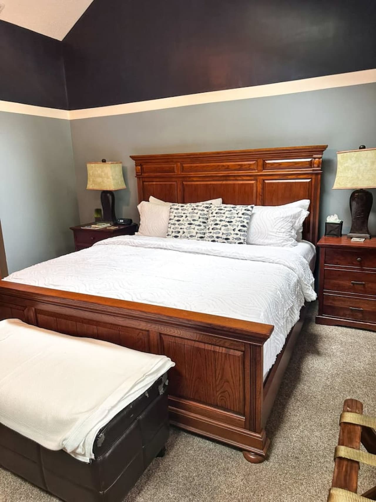This rustic bedroom features a massive bed, draped in a soft, cozy cover that invites you to relax and unwind. With its warm wood tones and simple, charming details, it offers the perfect mix of comfort and rustic elegance.