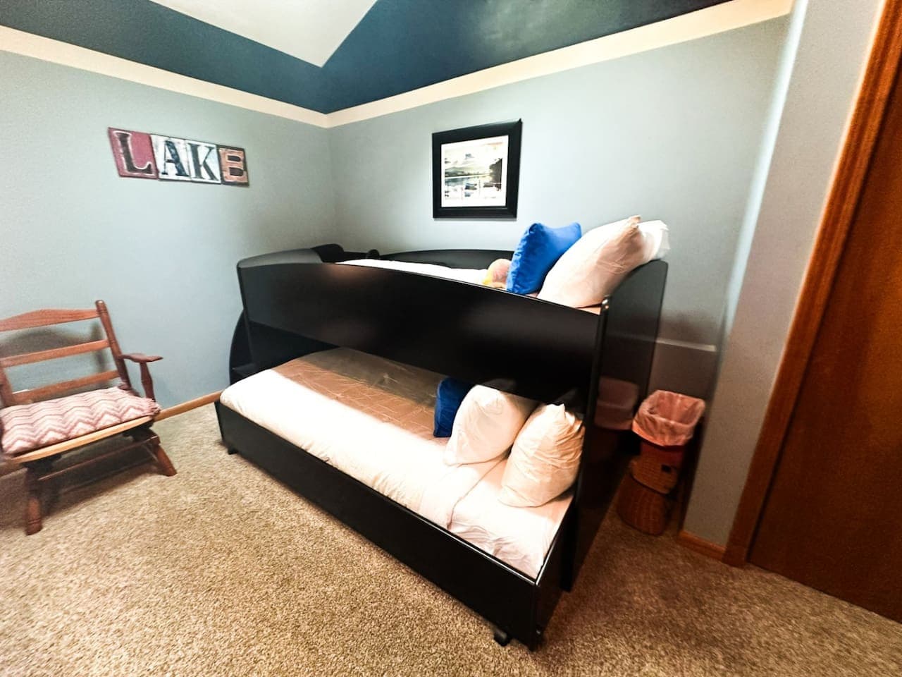This charming bedroom features sturdy bunk beds, perfect for a lake-themed retreat, with decor that evokes the serenity of the water. With calming blues and natural wood accents, it offers a cozy, playful space for guests or family to enjoy.
