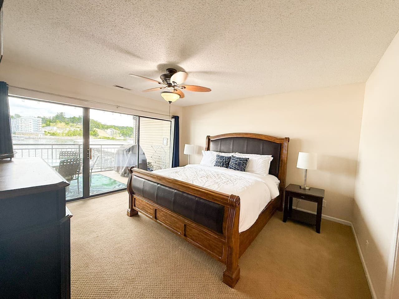 Relax in comfort in this inviting bedroom, complete with a large dresser and direct access to refreshing lake views.