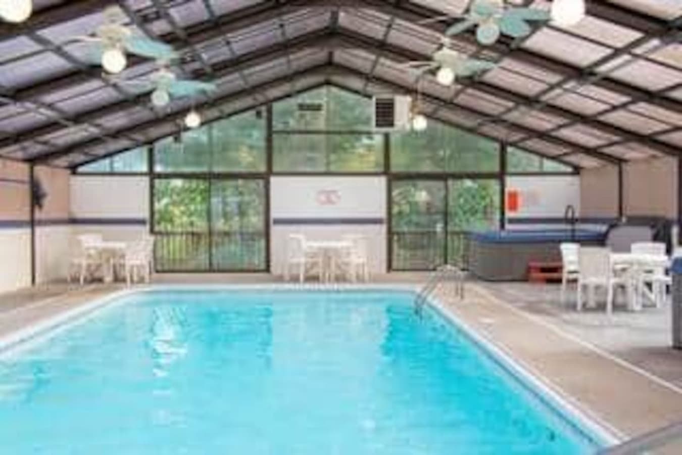 This rental boasts a fantastic indoor pool area, complete with a large swimming pool and a relaxing hot tub for year-round enjoyment. The bright and spacious enclosure, featuring numerous windows and ceiling fans, creates an inviting atmosphere perfe