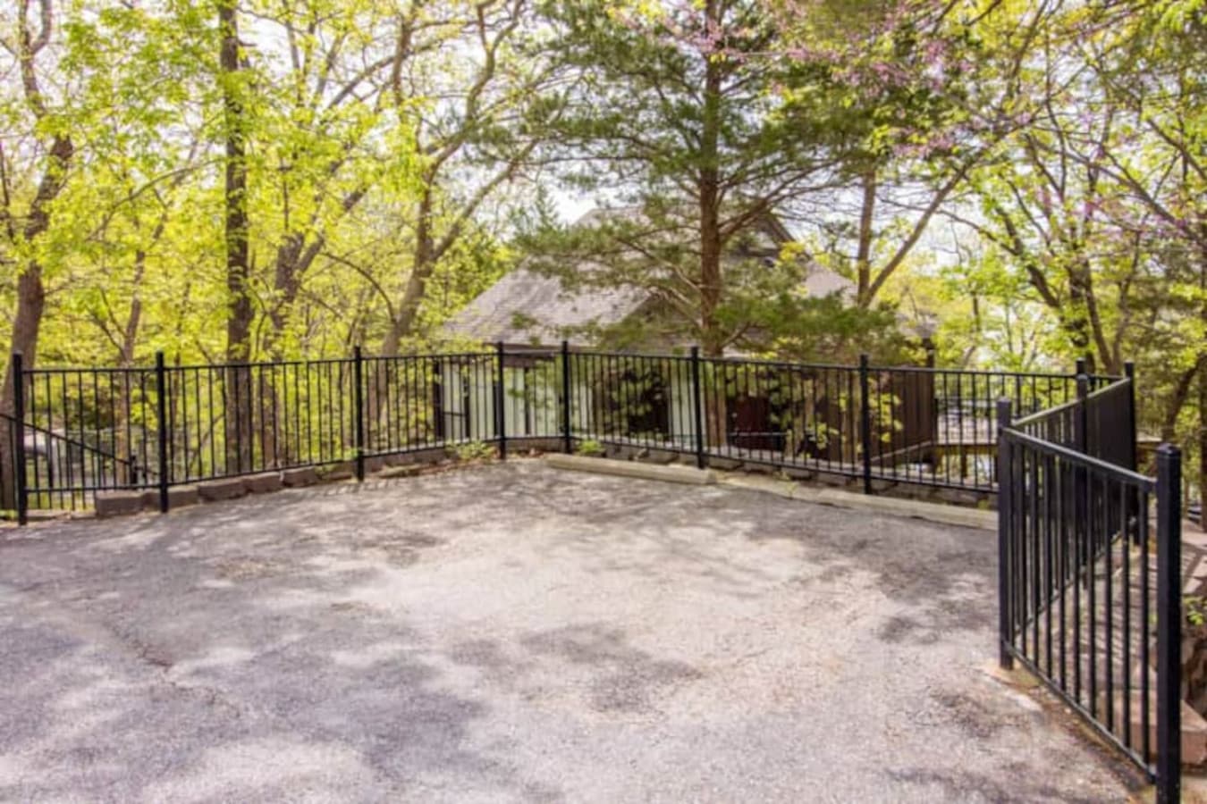 private parking that is well-maintained outdoor space featuring a secure black metal fence and smooth asphalt paving. This space blends functionality with scenic beauty."