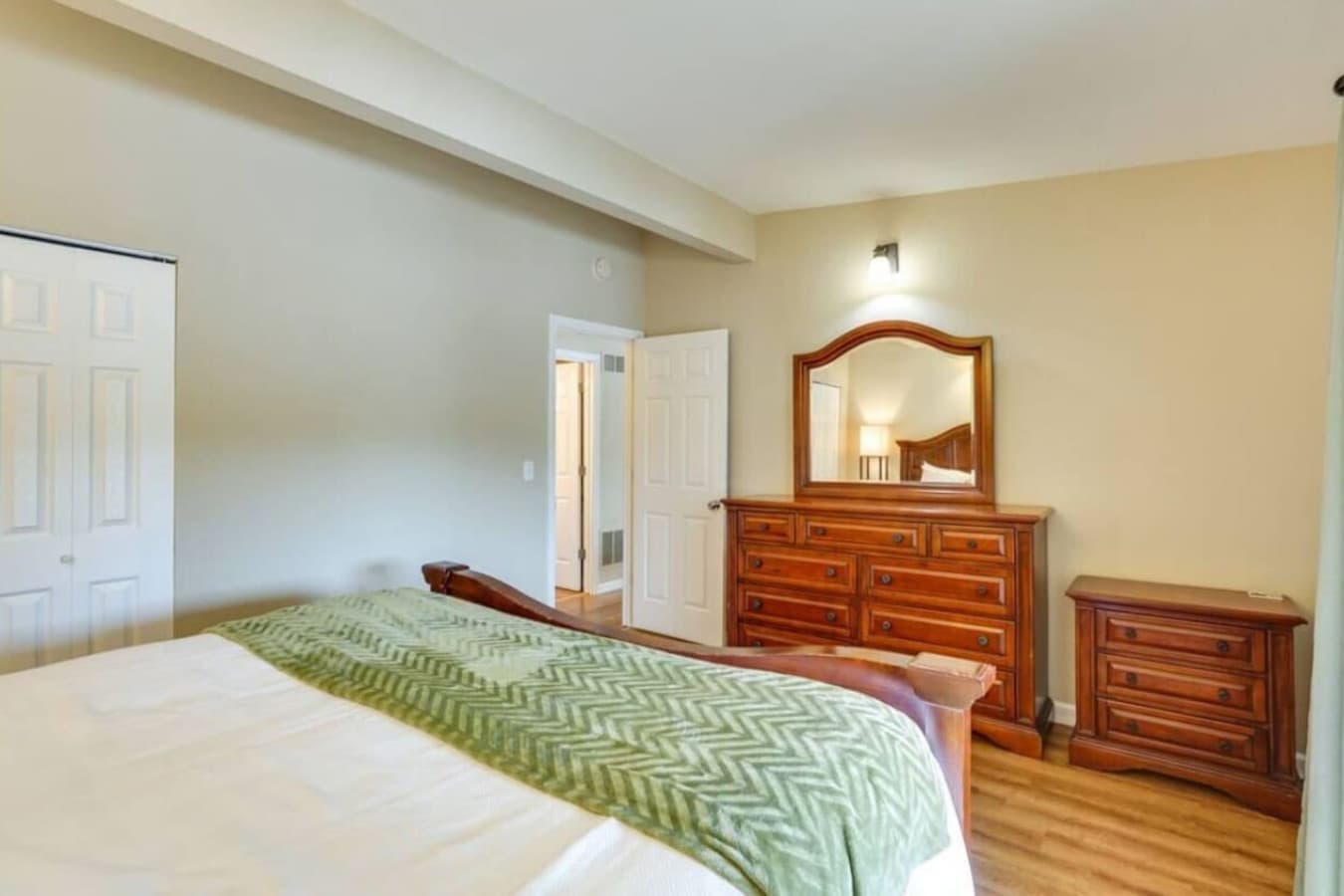 This elegant master bedroom features a luxurious bed, wood furniture, and access to a private deck.