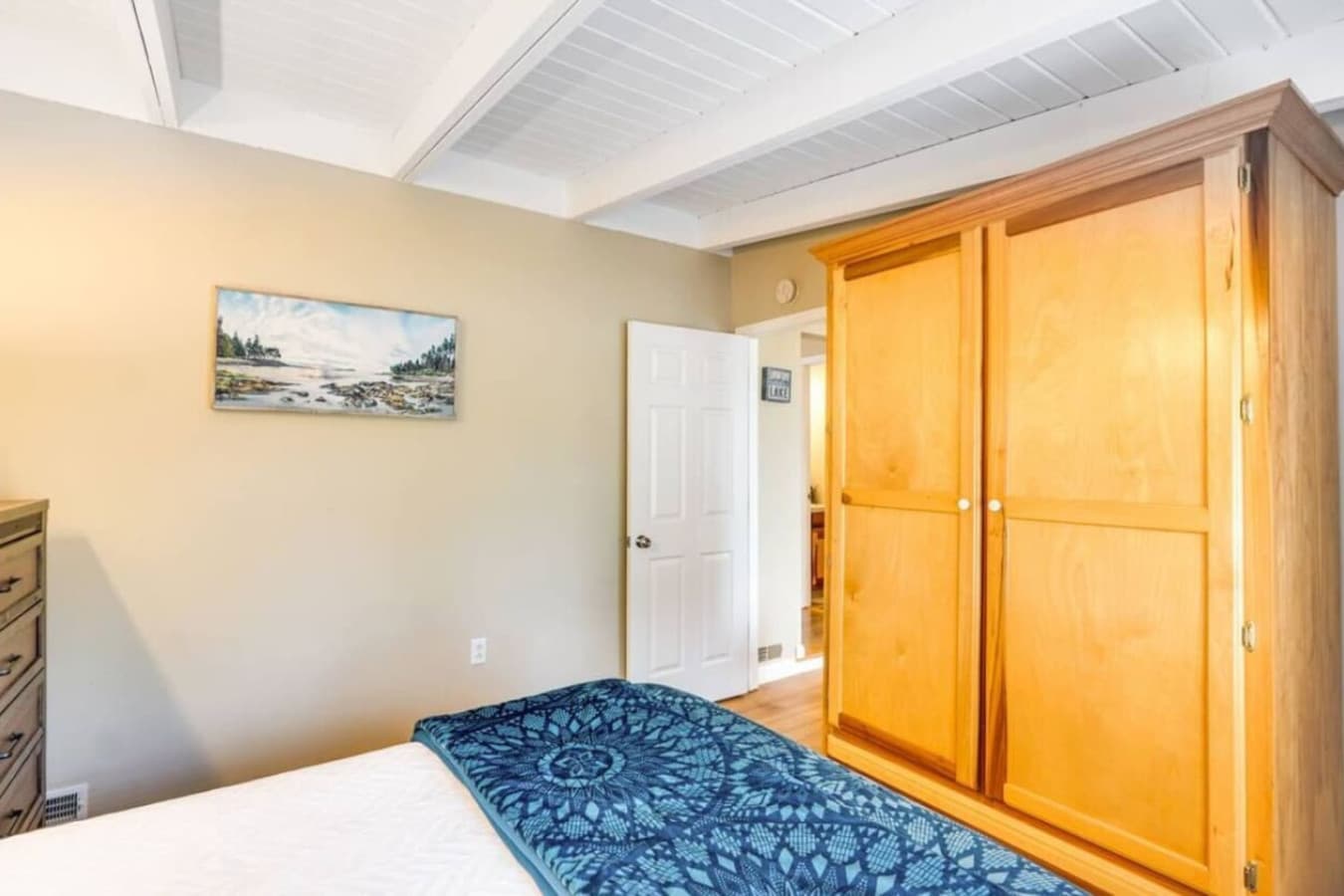 The bedroom boasts a large wooden wardrobe and serene wall art, combining functionality with a tranquil ambiance.