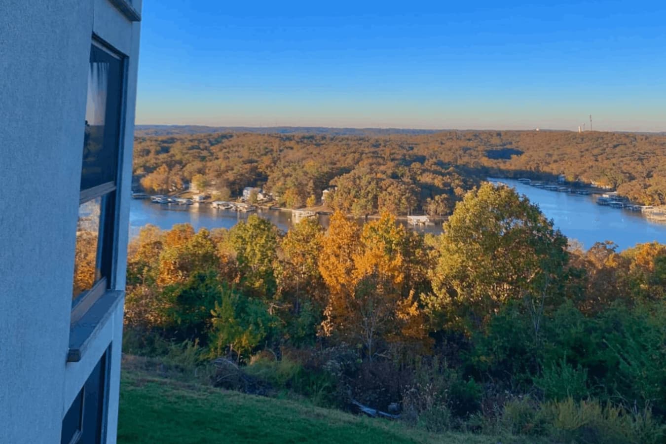 Perched on a serene hillside, this inviting property offers stunning panoramic views of the Lake of the Ozarks, surrounded by vibrant fall foliage.