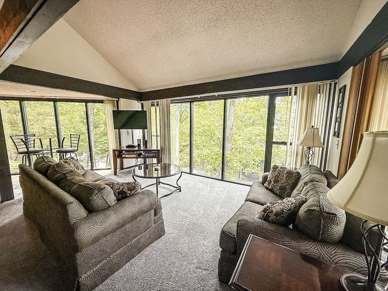 Couch so cozy it practically hugs you, while floor-to-ceiling windows frame a view so stunning, even the birds pause mid-flight to admire it.