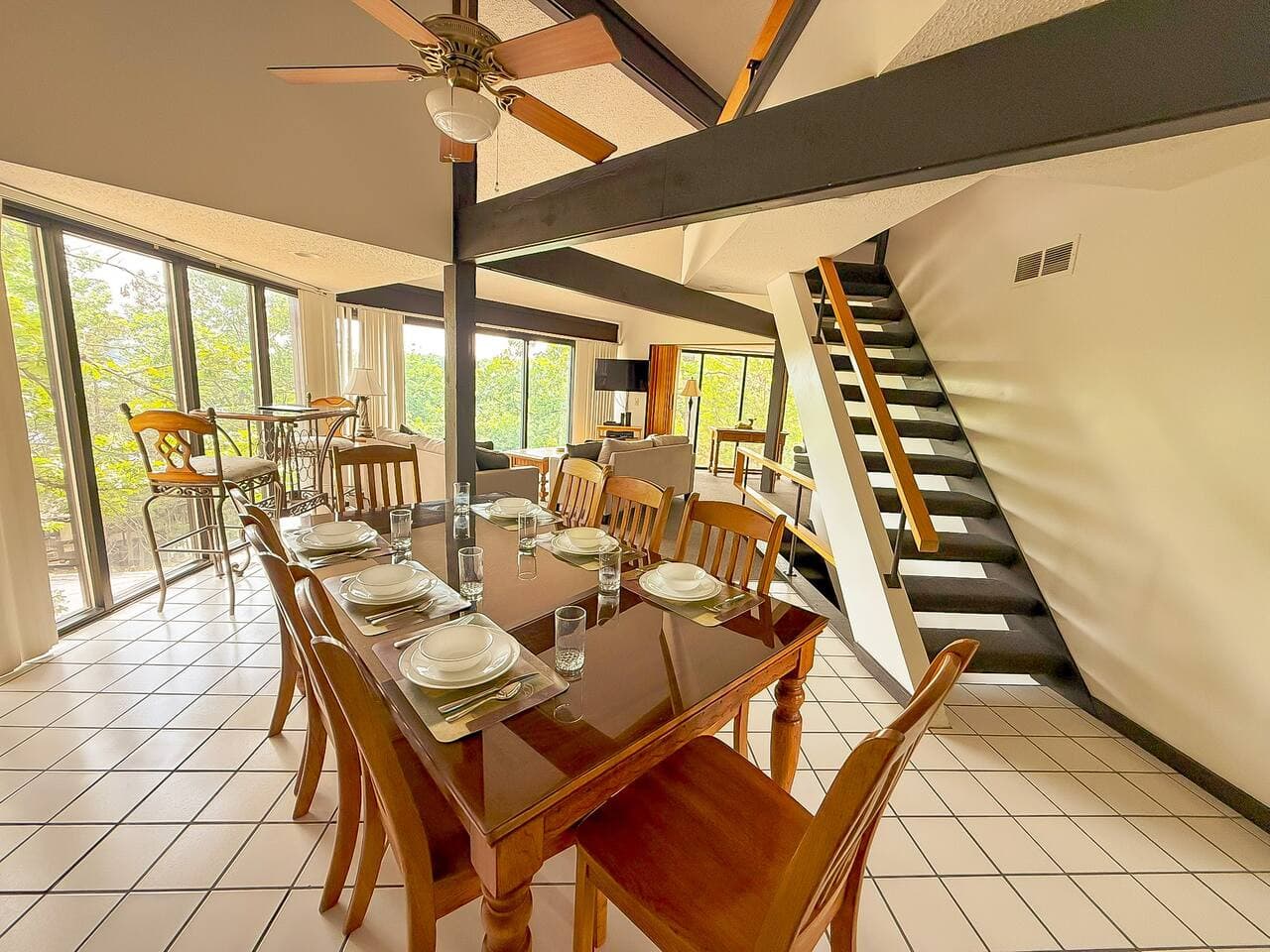 An eight-seater dining area and a bar table with chairs in the corner, offering stunning nature views, this space combines comfort, style, and convenience for a perfect gathering spot.