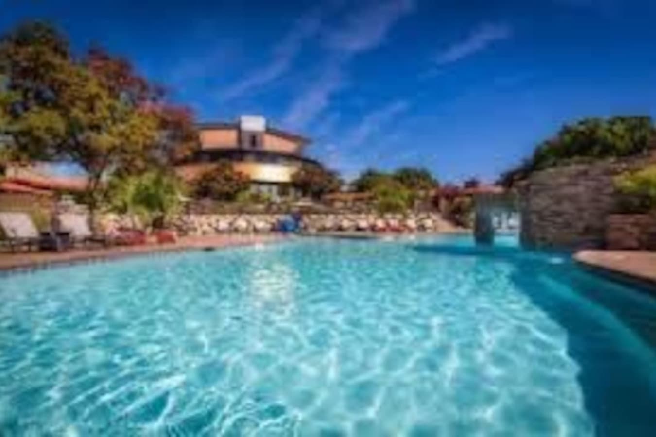 Enjoy resort-style amenities with access to a stunning outdoor pool featuring a cascading waterfall, surrounded by lush landscaping and plenty of lounge seating. Whether you're sunbathing or taking a refreshing dip, this beautifully maintained space