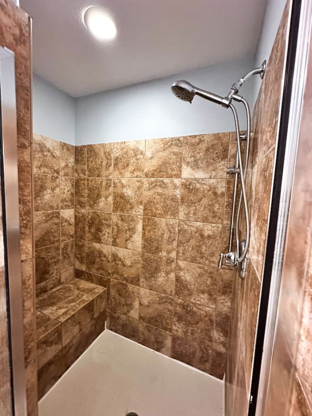 Enjoy a rejuvenating shower with modern tile design and a built-in bench for added comfort.