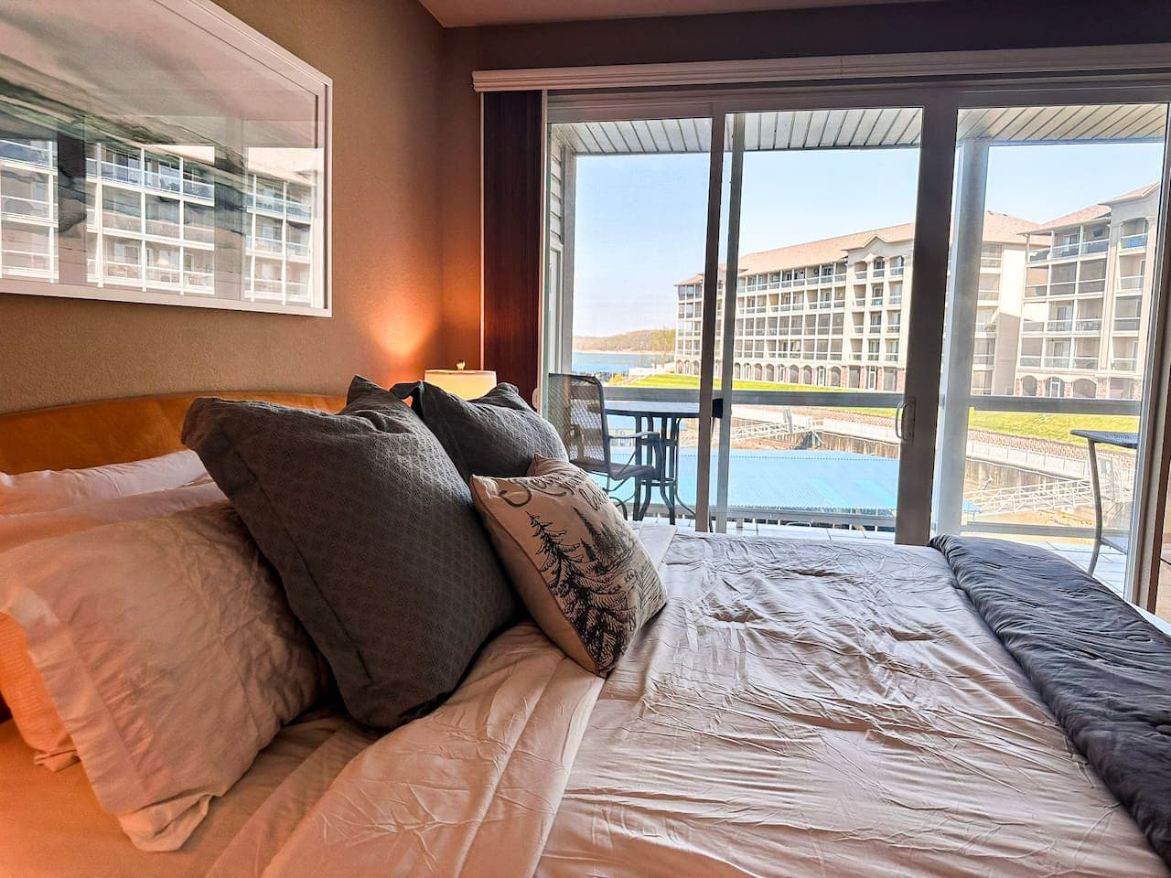 This beautiful bedroom offers direct access to a private balcony, providing stunning views of the serene waters and surrounding buildings. Enjoy comfortable accommodations with ample natural light, perfect for a relaxing stay.