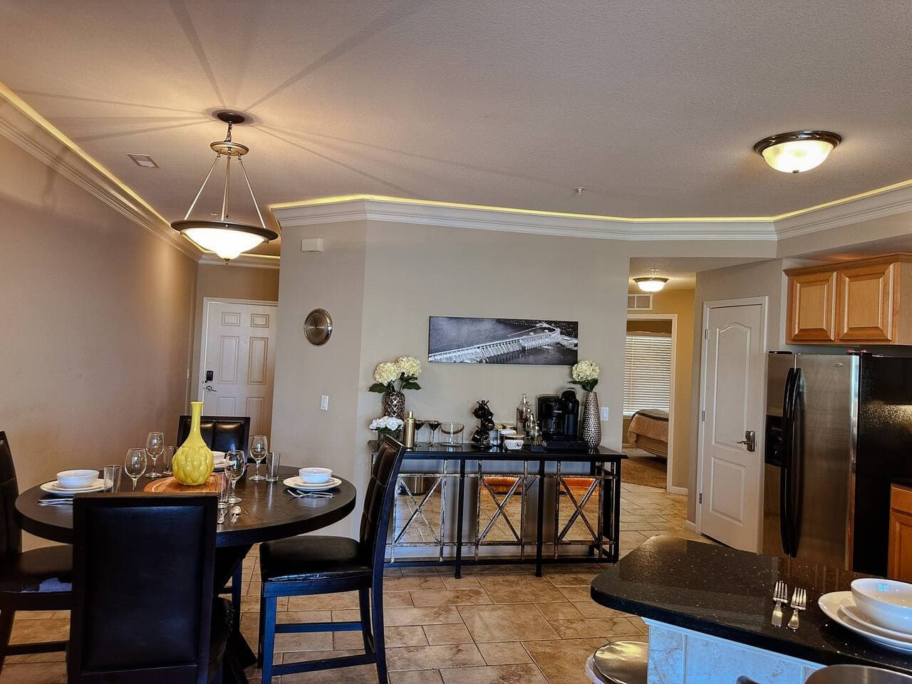 This bright and inviting dining area features a large, dark wood table ready for your meals, complemented by stylish black chairs. Overhead, a charming pendant light illuminates the space, creating a warm and welcoming ambiance for gatherings.