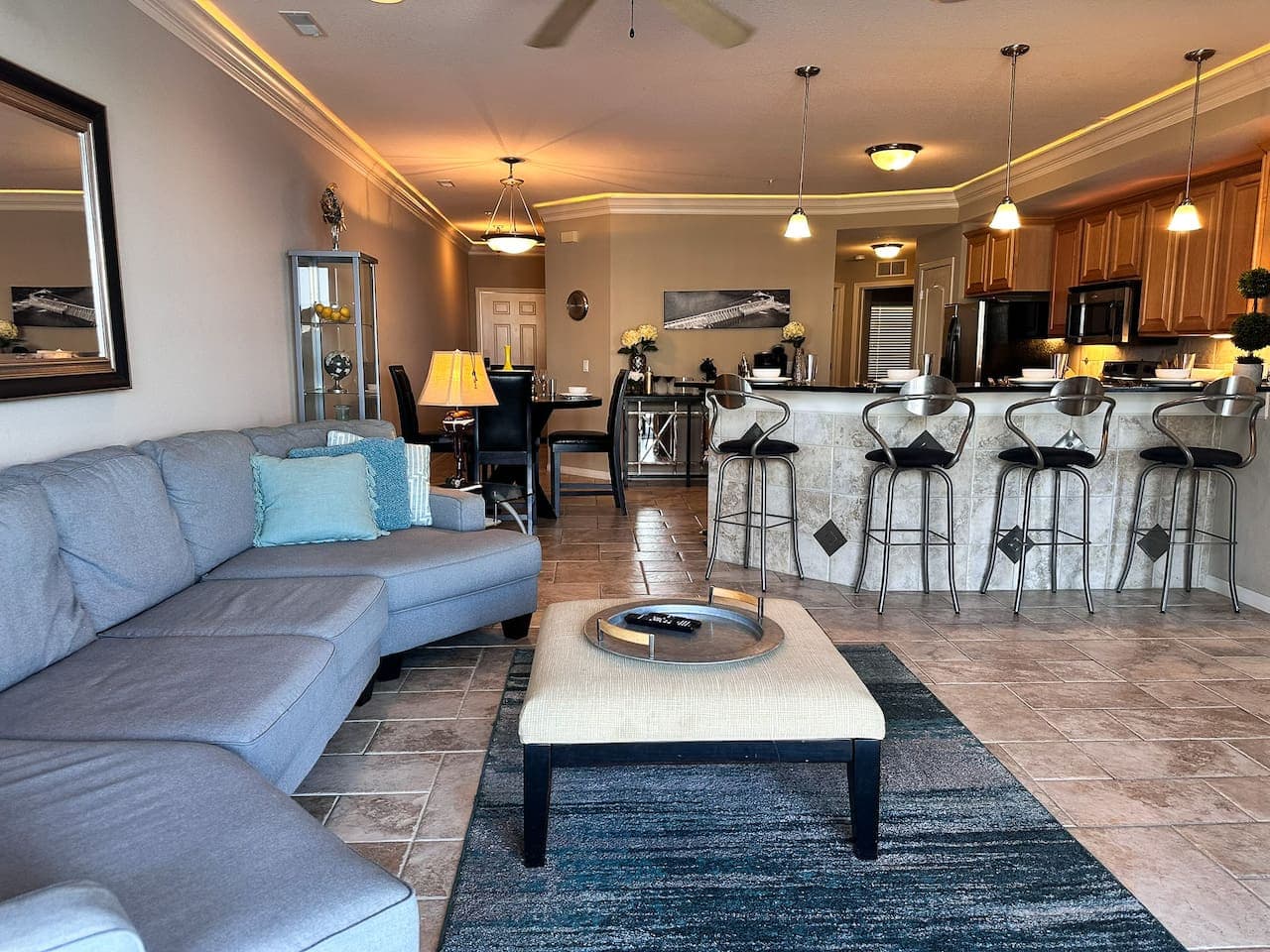 This open-concept living space seamlessly combines comfort and style, featuring a plush sectional sofa and a large area rug, perfect for relaxing. The well-appointed kitchen with a breakfast bar and pendant lighting creates an inviting atmosphere for