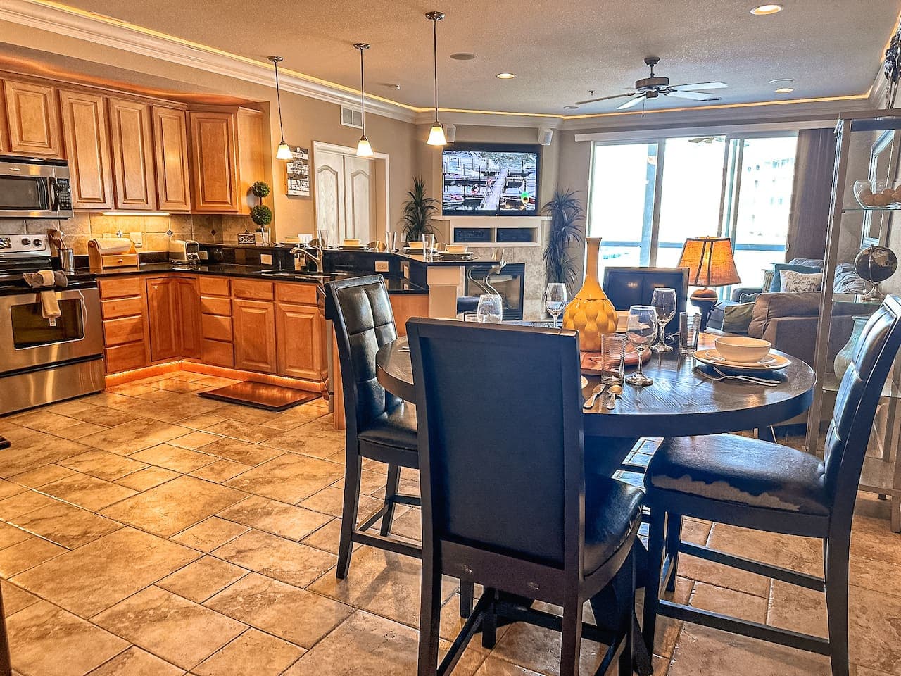 This modern kitchen boasts sleek dark cabinetry and stainless steel appliances, providing a stylish and functional space for all your cooking needs. The expansive countertop offers ample preparation area, while the open design integrates seamlessly w