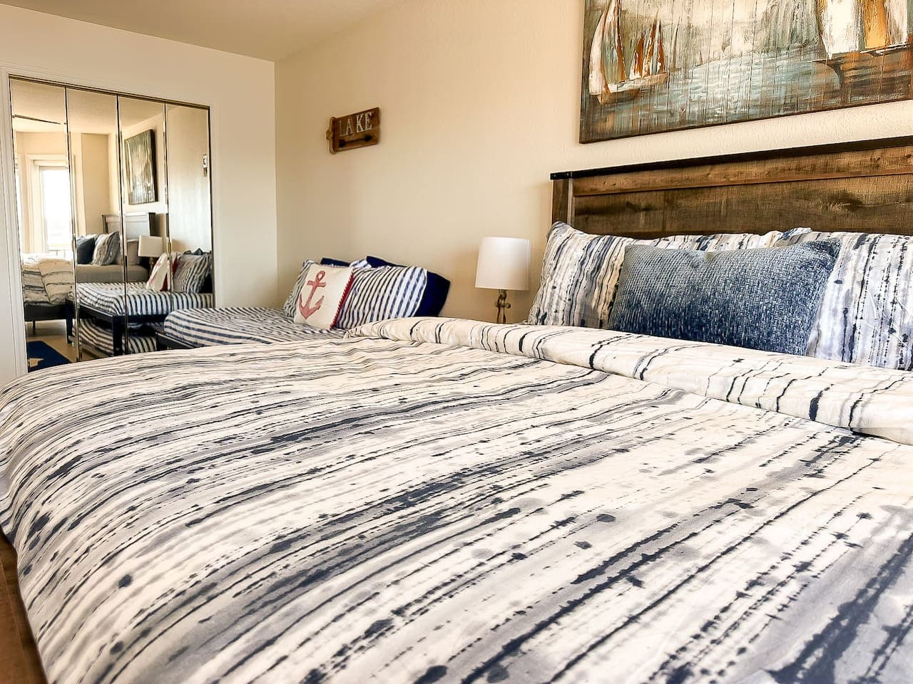 Wake up to breathtaking lake views in this beautifully styled bedroom, featuring soft nautical tones, modern decor, and direct patio access.