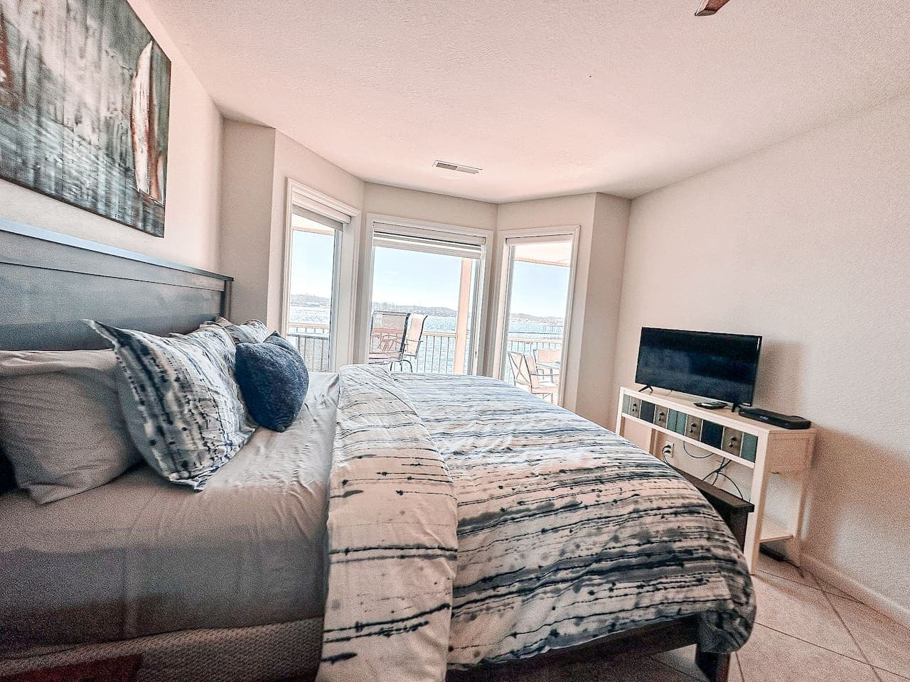 A comfortable bedroom with a plush bed, inviting decor, and stunning lake views through the large windows.