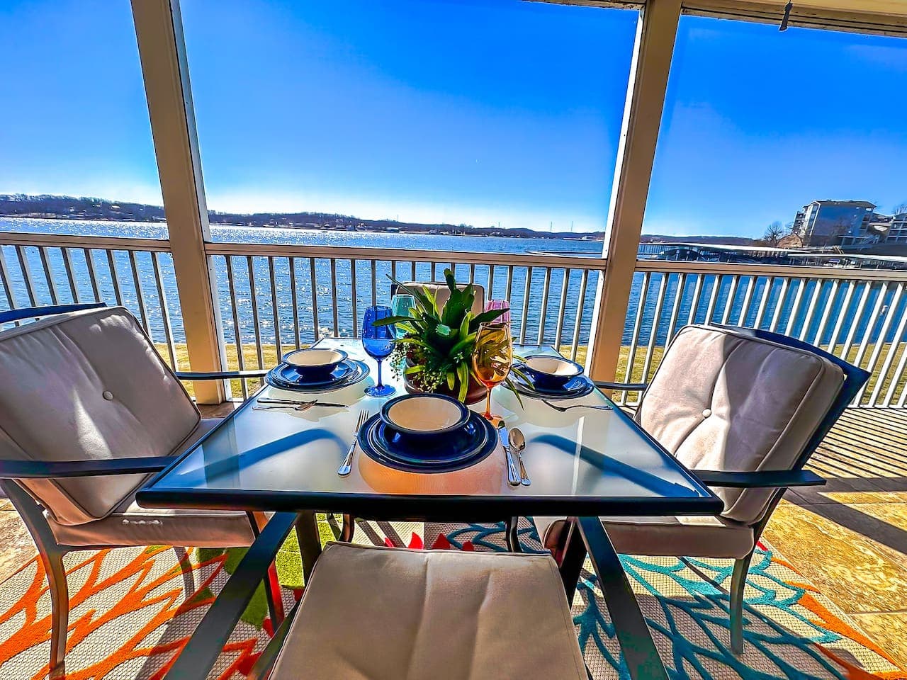 A perfectly set table with elegant blue-themed dinnerware, overlooking the sparkling waters of the lake.