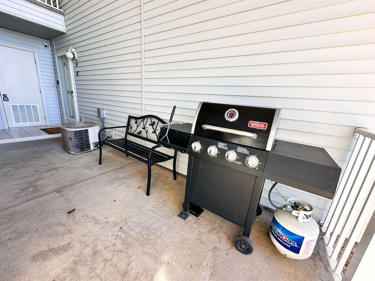 A shaded outdoor space with a propane BBQ grill and a comfortable bench, providing a great spot to cook and relax just steps from your condo entrance.