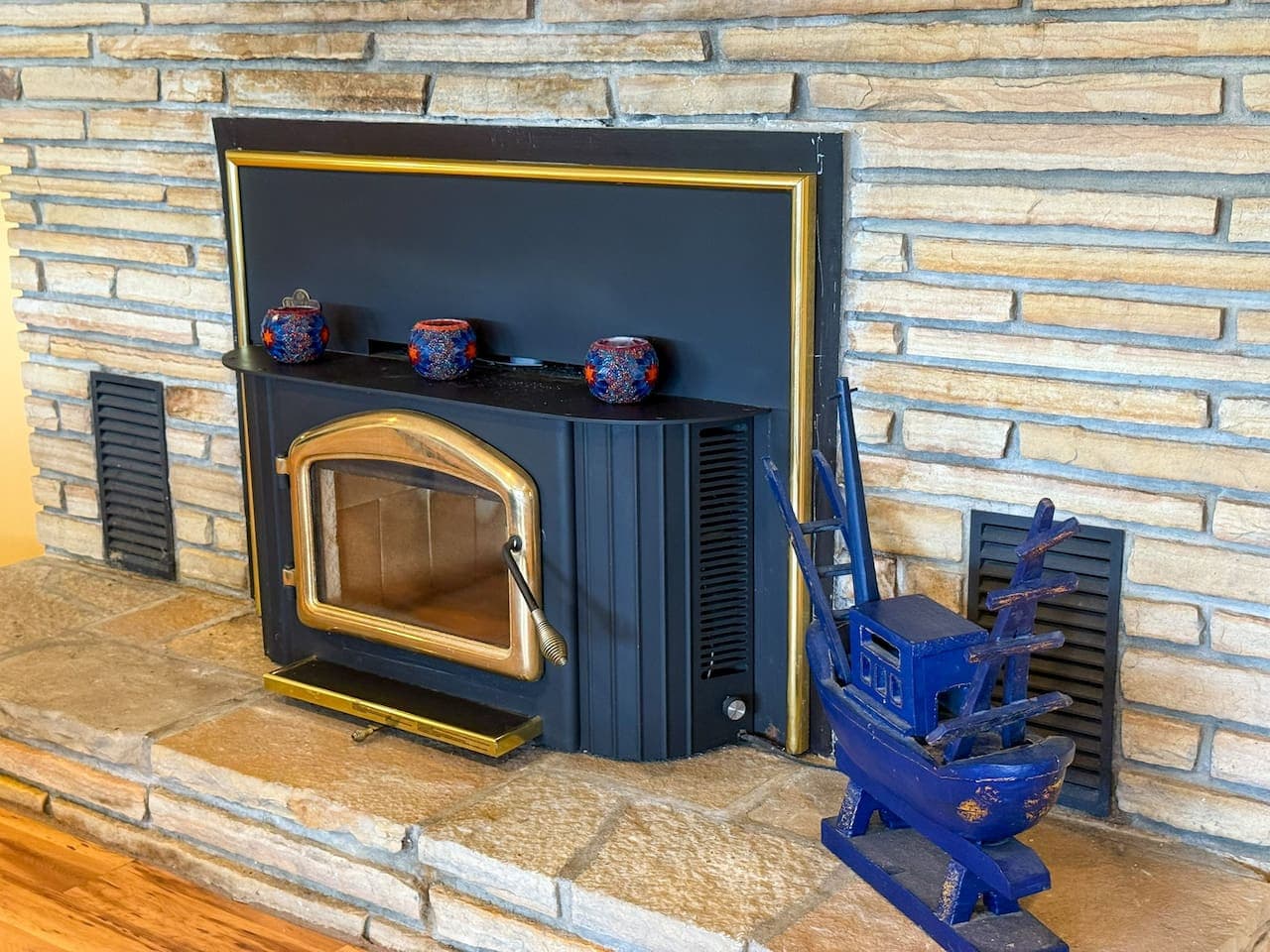 Vintage-style fireplace framed in black and gold, with a charming setup.