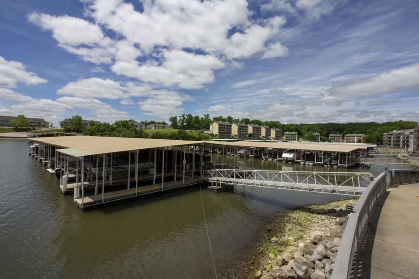 A spacious boat dock with covered slips and easy walkway access by the water’s edge.