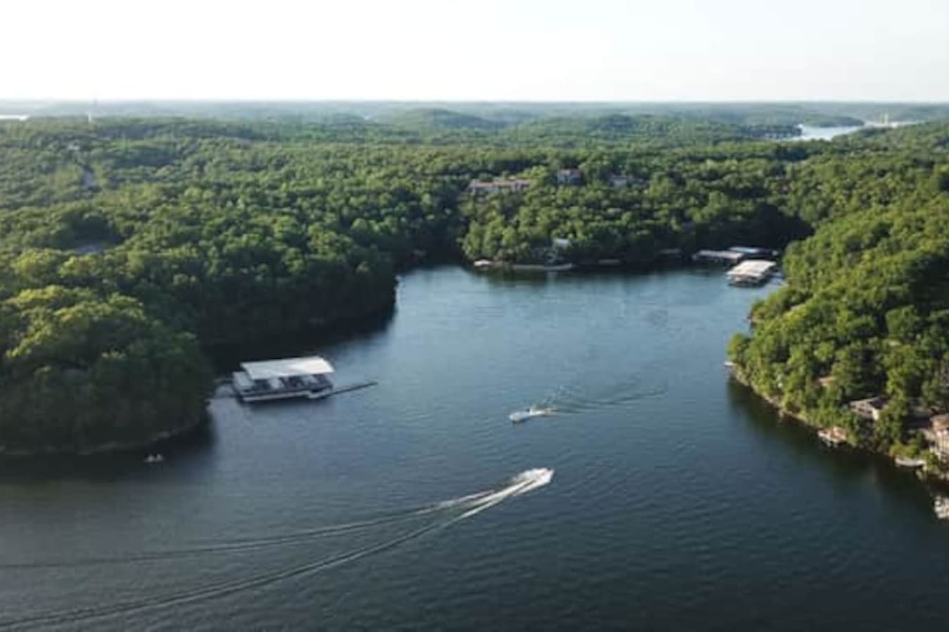 This expansive aerial view showcases the stunning Lake of the Ozarks, surrounded by vibrant fall foliage, offering a truly picturesque setting. The property boasts multiple boat docks, providing convenient access to the water for all your aquatic adv
