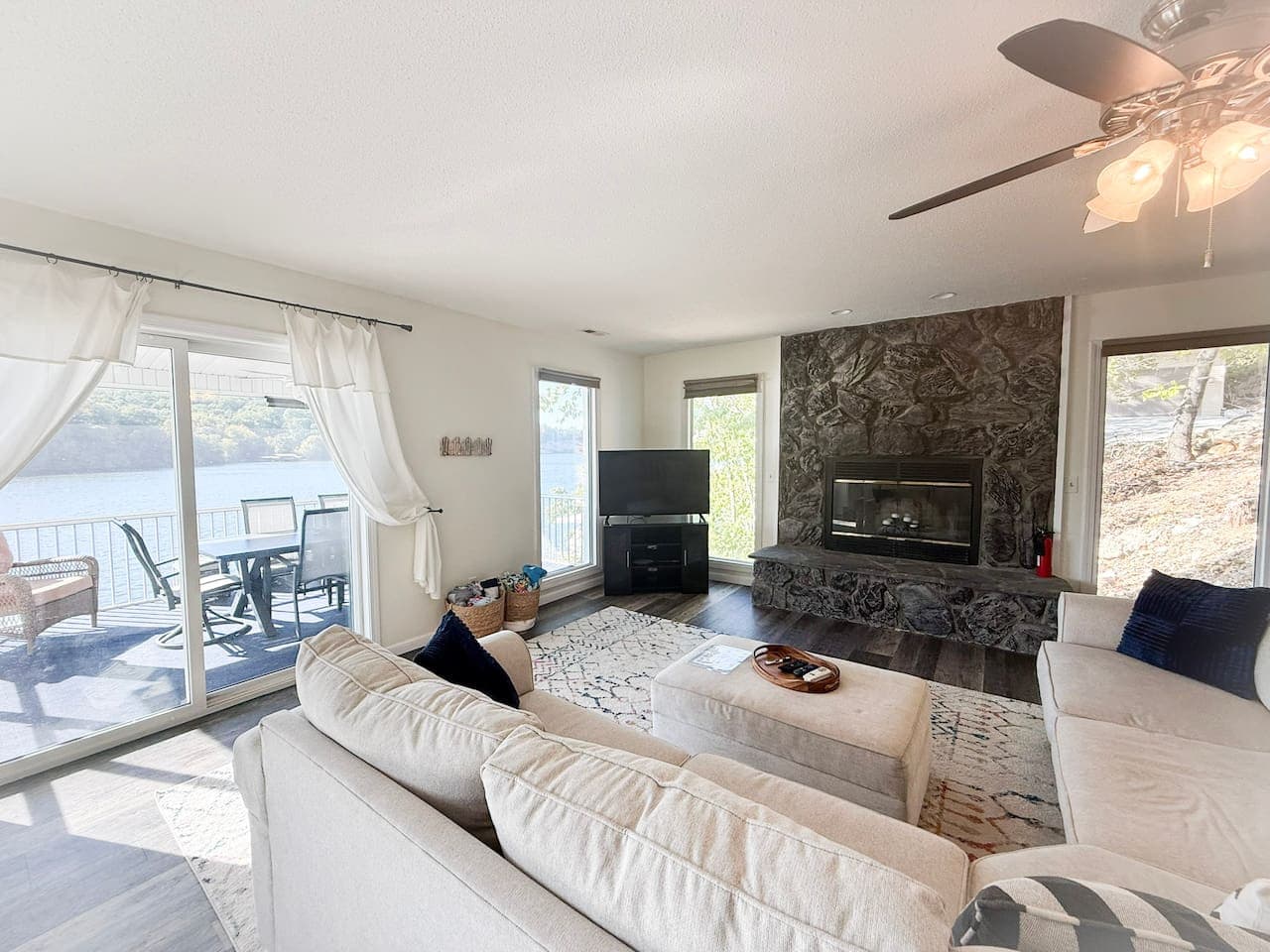 Relax in the airy living room featuring lake views, a stone fireplace, and comfy seating for the whole group.