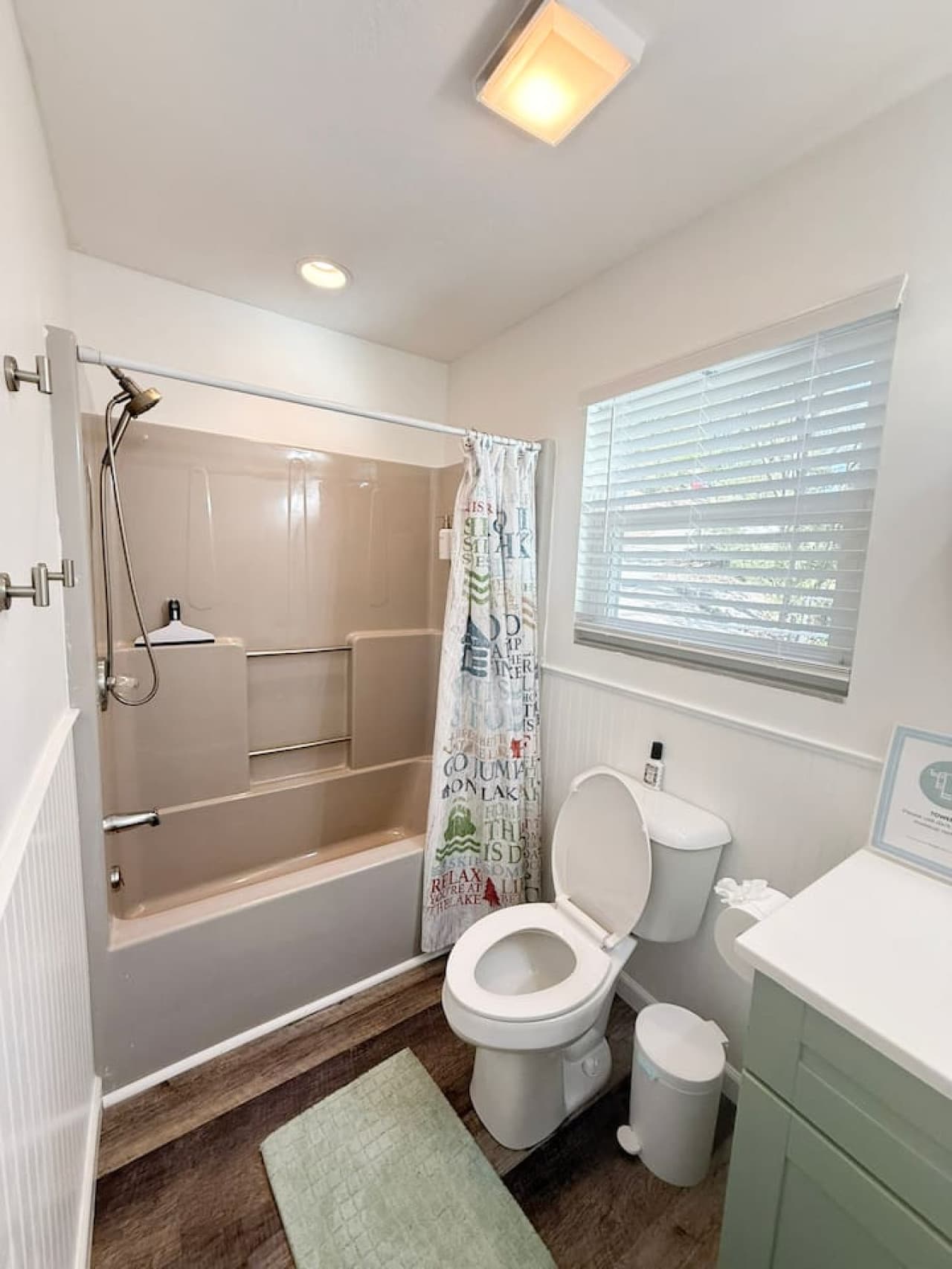 Bright and spotless bathroom with natural light, full shower, and cozy modern touches.