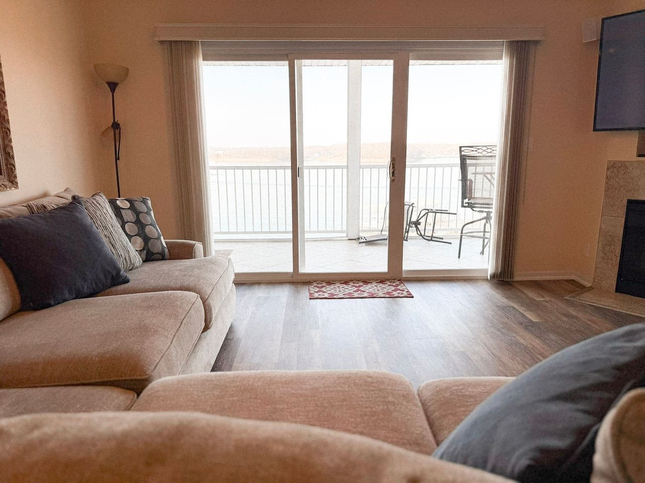 Step into a bright lakefront living space with panoramic water views, opening to a private balcony for fresh air and sunsets.