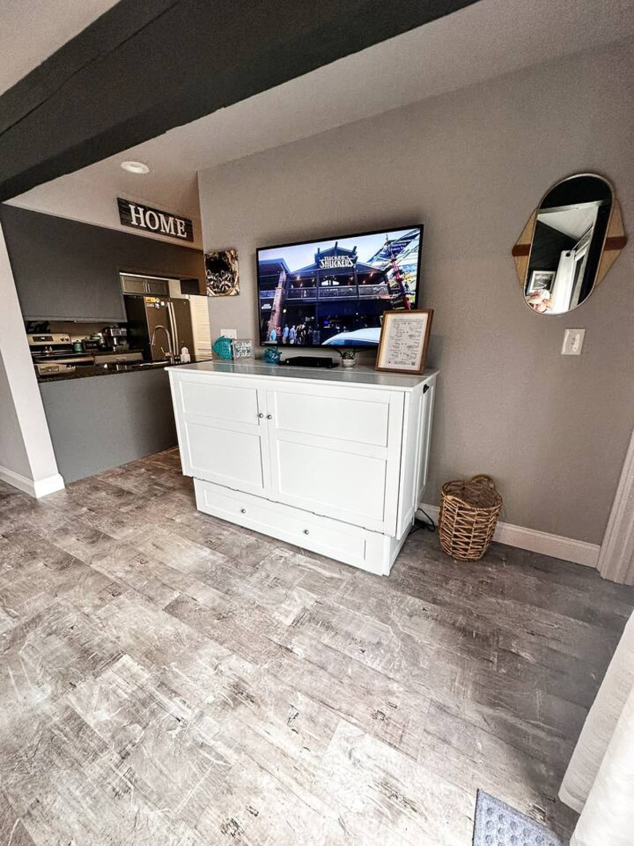 The sleek white console not only provides a stylish stand for the TV but also doubles as a full-size Murphy bed, seamlessly transforming the space for additional sleeping accommodations.