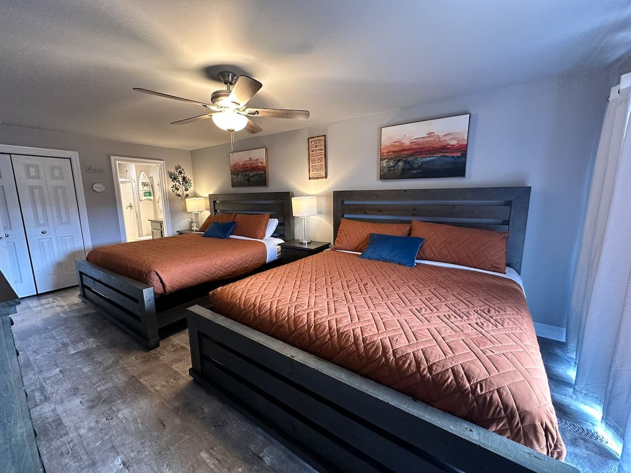 A wider angle of the bedroom highlights the modern design, thoughtful decor, and ample natural light streaming in through the windows.