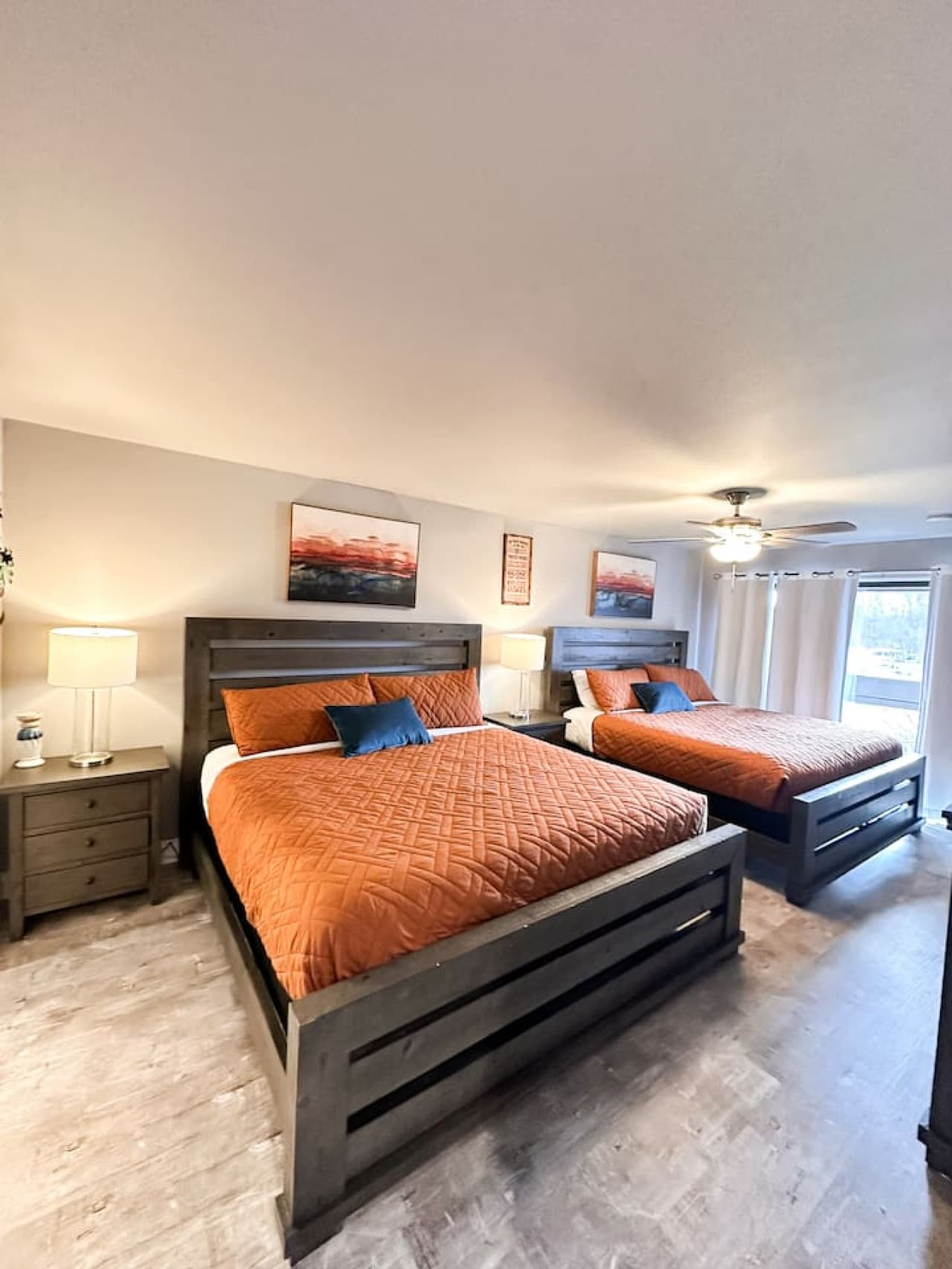 Bedroom offers two king-size beds, creating a spacious and cozy retreat for multiple guests, adorned with calming wall art and warm lighting.