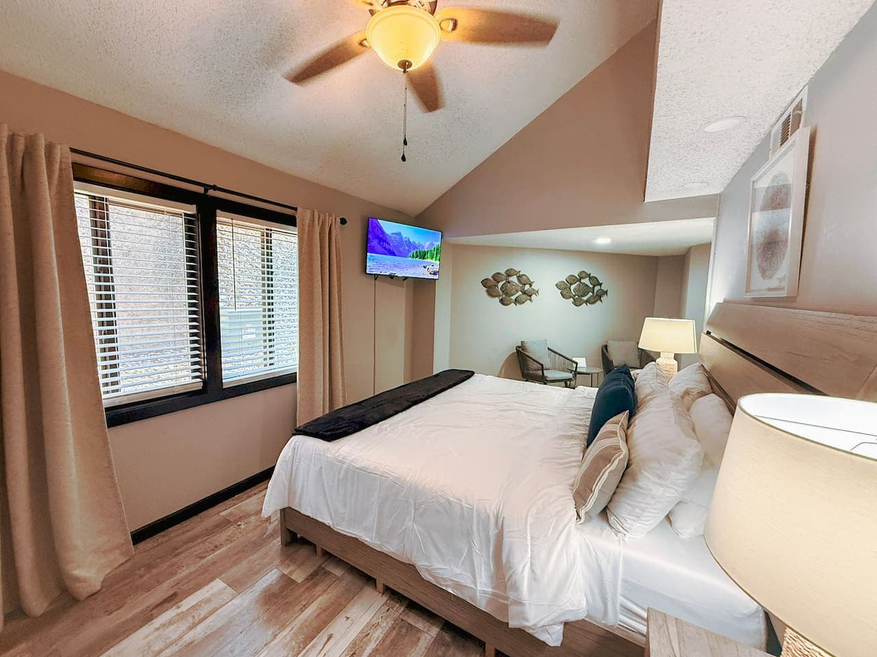 Cozy king bedroom with TV and soft natural light.