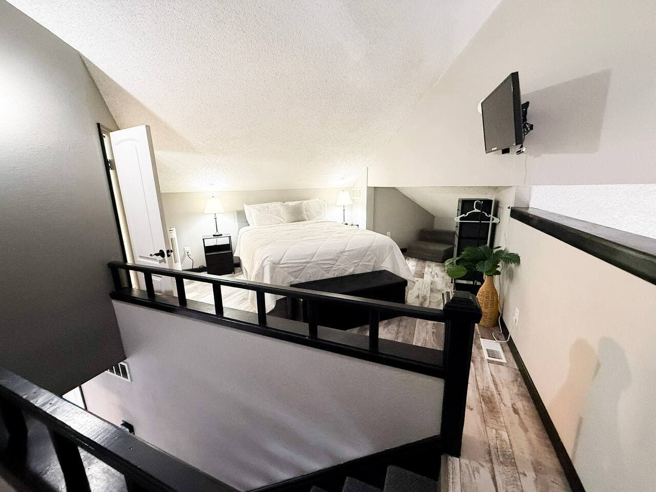 Cozy loft bedroom with plush bedding and a TV.