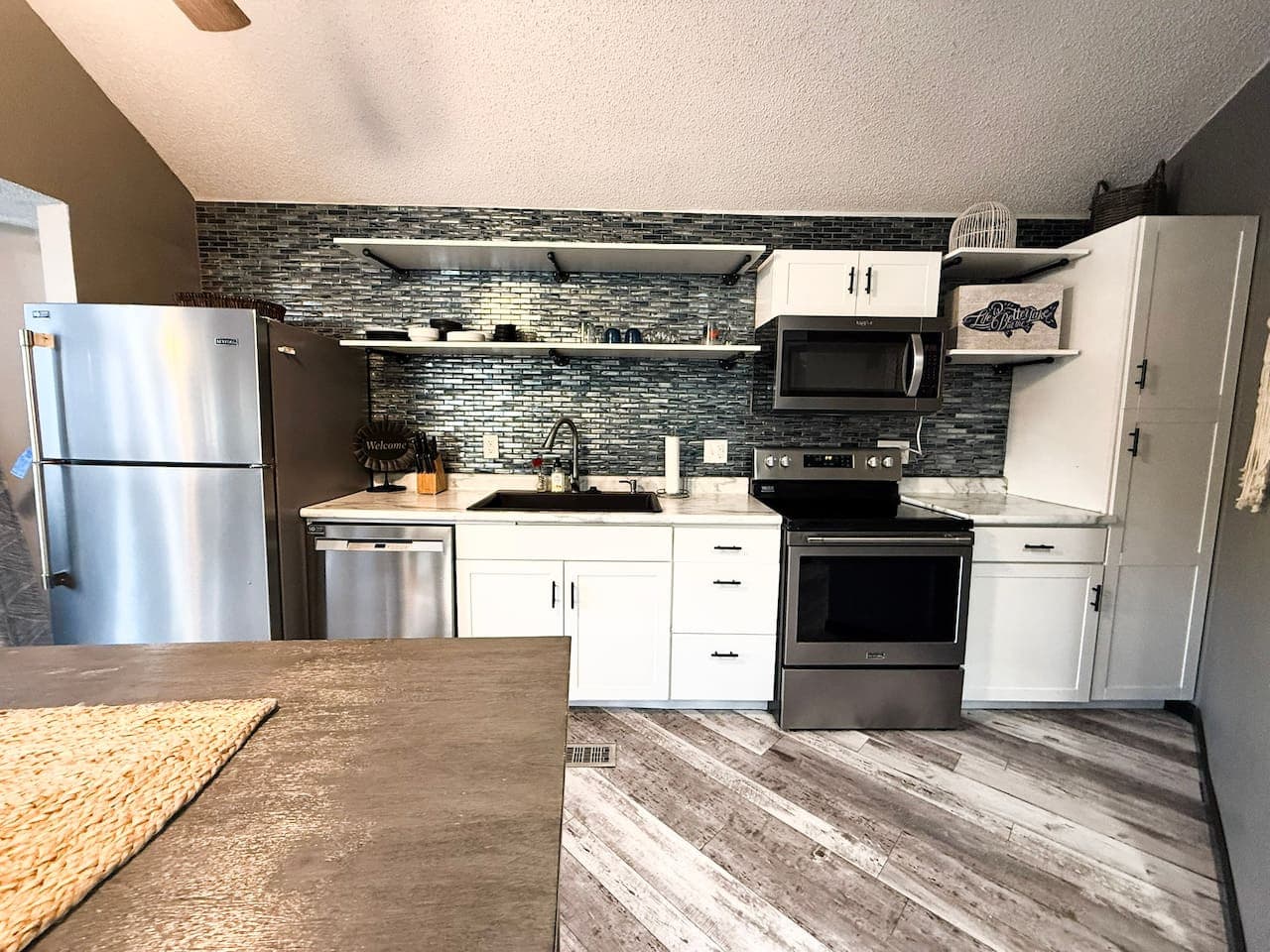 Fully equipped kitchen with open shelving and modern finishes.