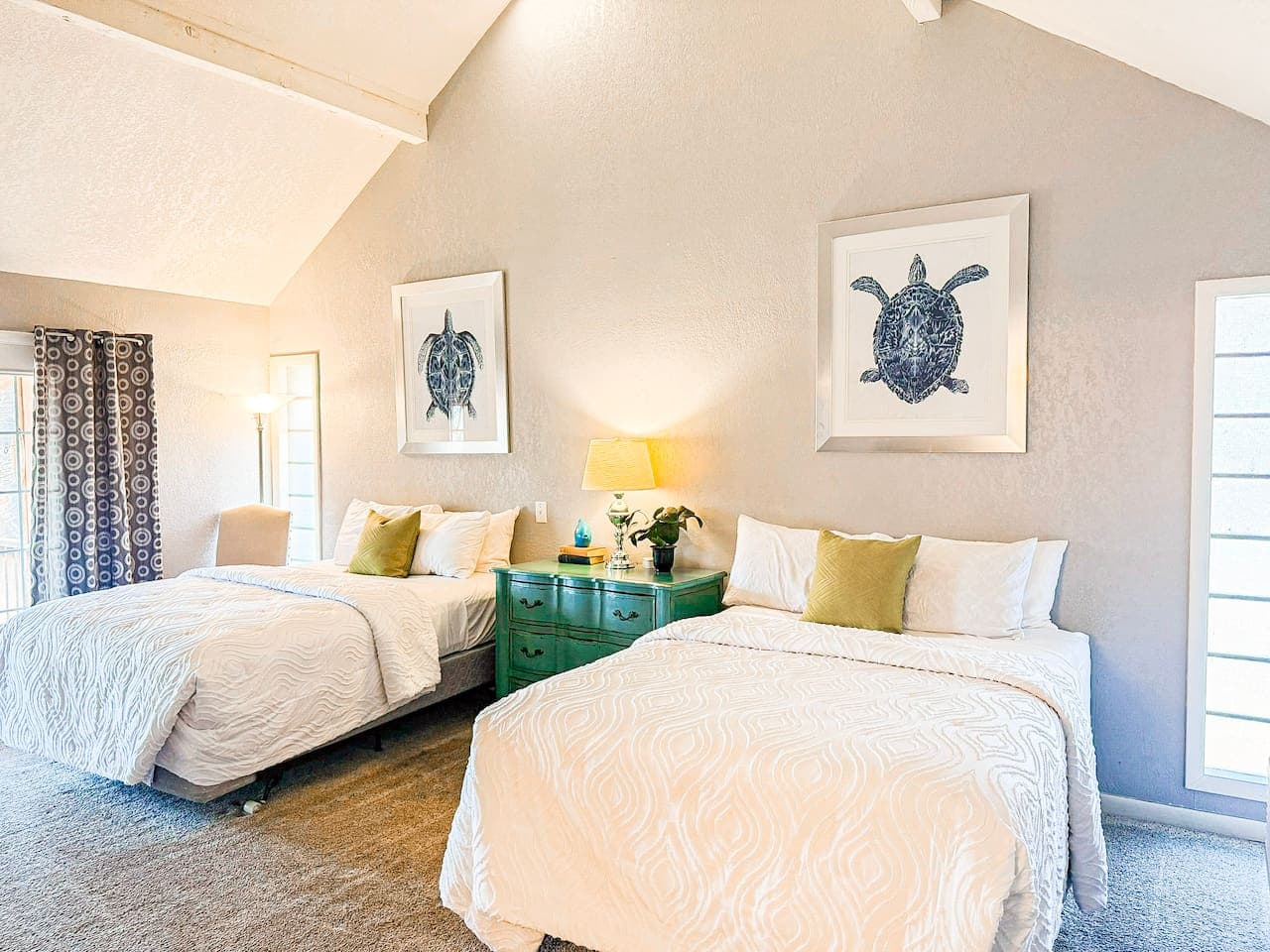 Relax in a spacious, sunlit bedroom featuring two cozy beds, soft linens, and serene coastal-inspired décor. Perfect for families or groups seeking comfort, style, and a peaceful retreat.