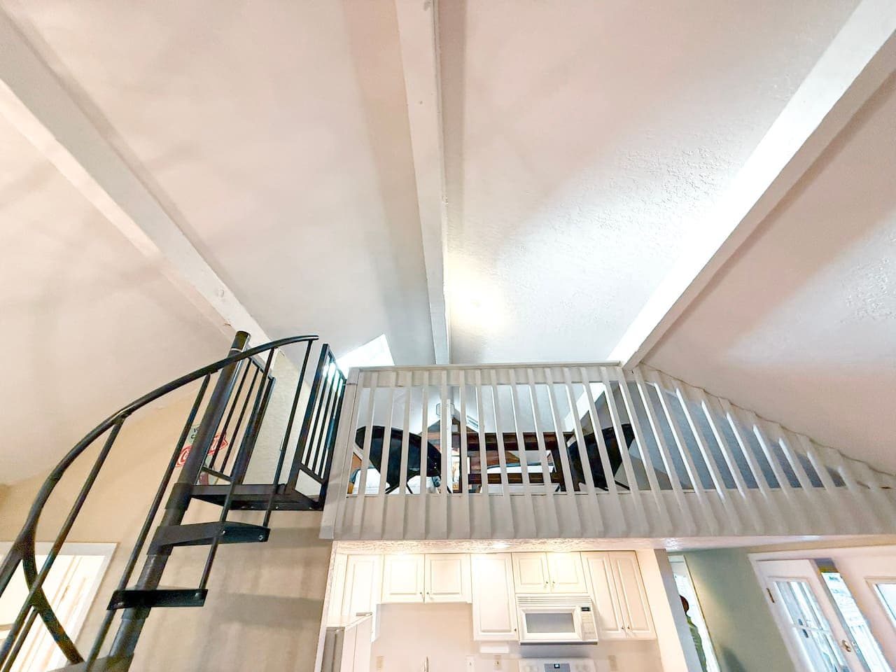 Relax in a beautiful loft overlooking the living area, featuring high ceilings and a striking spiral staircase. A guest favorite for its charm, openness, and inviting atmosphere.
